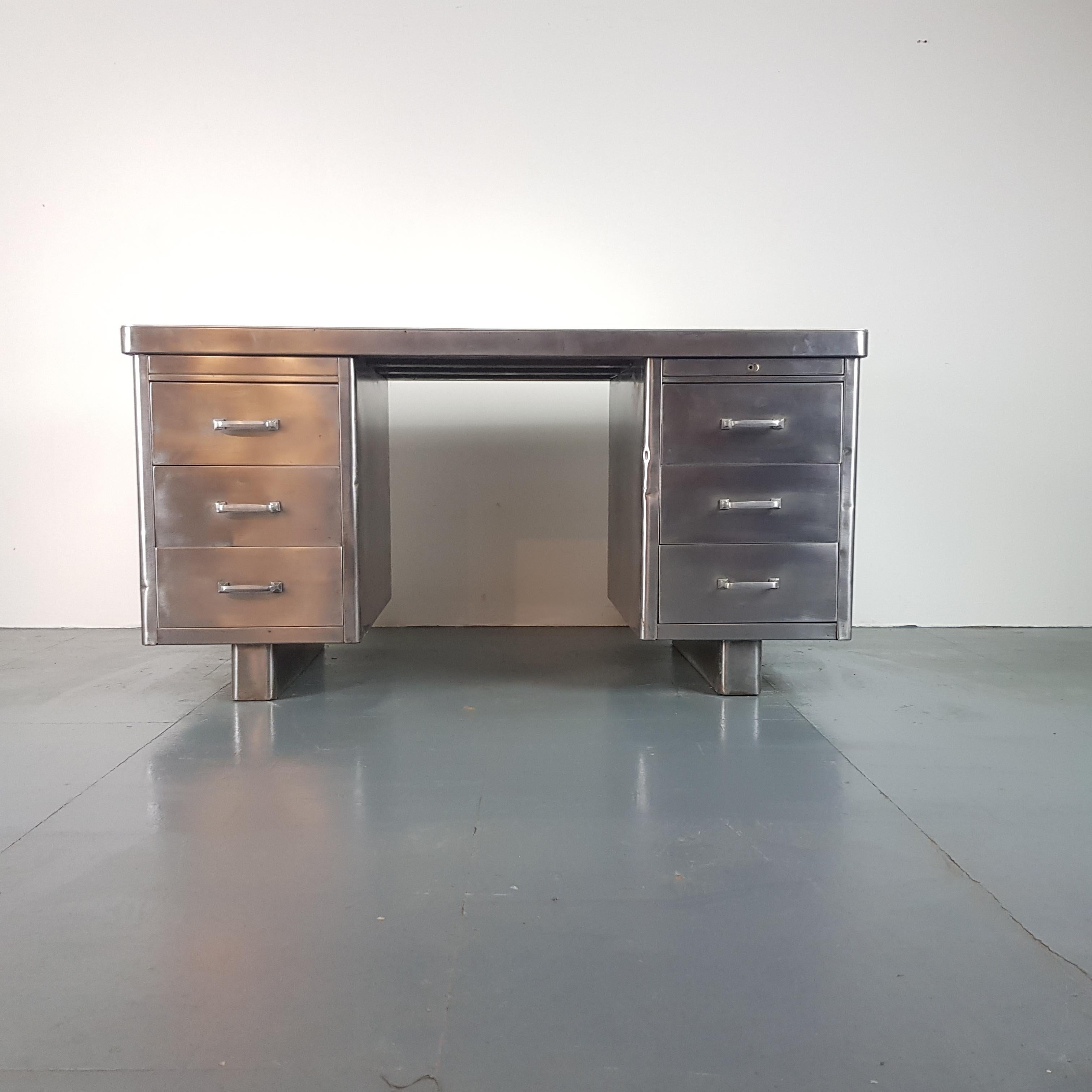 Lovely vintage double pedestal polished steel desk.

In good vintage condition - this piece comes from a working industrial environment and as such, has signs of wear and tear commensurate with age i.e bumps, scuffs etc, all adding to the