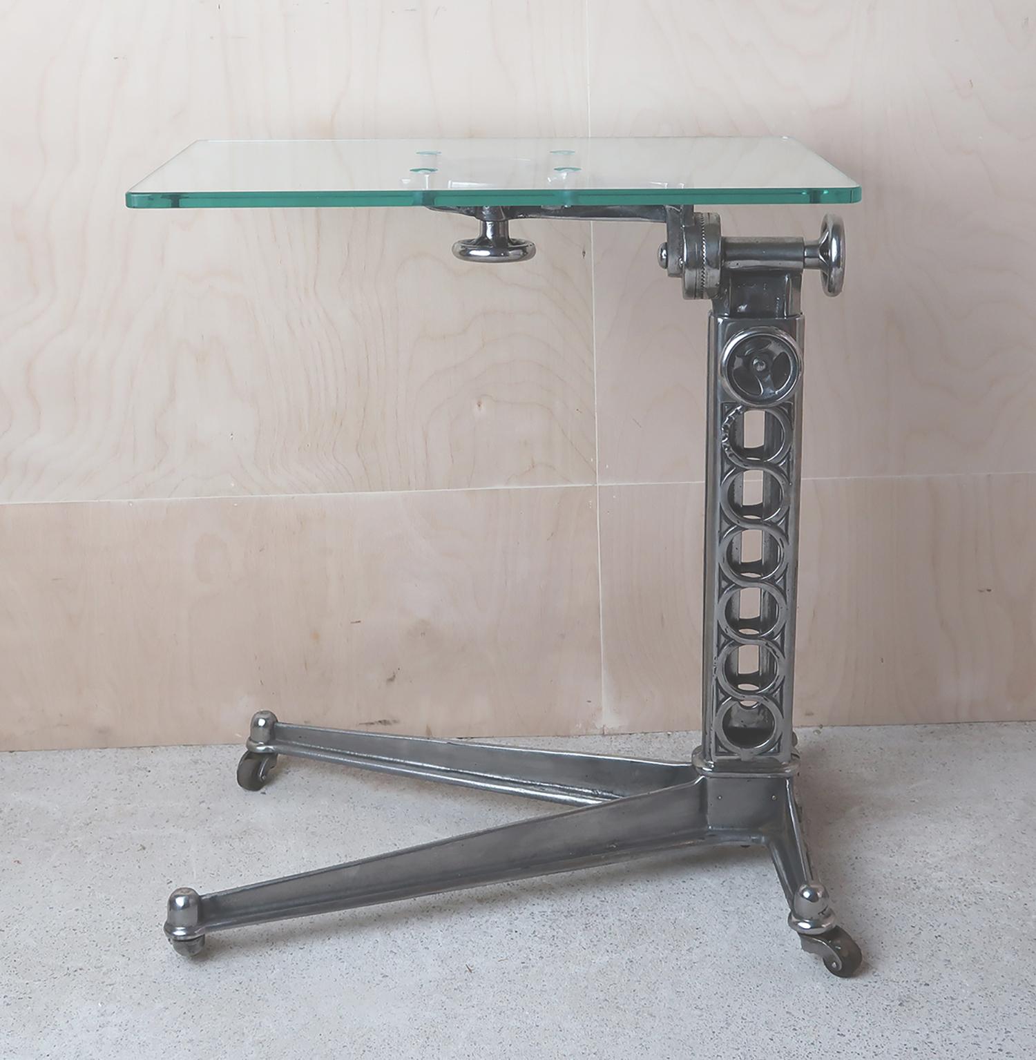 Stylish side or work table with an elegant Industrial look.

Made of cast iron (recently highly polished) with a new toughened glass top.

On original pot castors the table is easily pushed around the room.

The top is adjustable to a maximum of 36