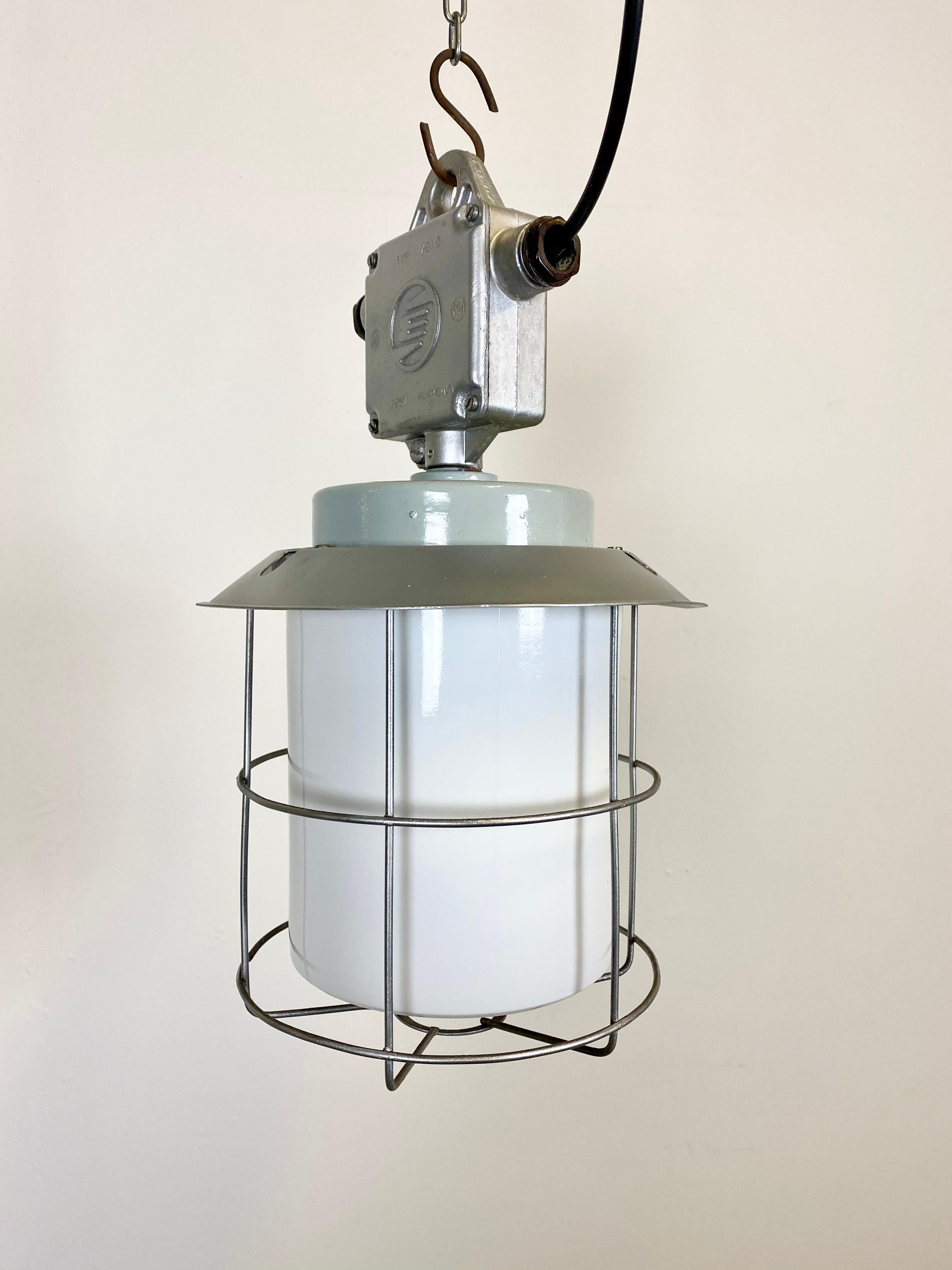 This industrial lamp in aluminium with milky glass was produced by Elektrosvit in former Czechoslovakia during the 1970s. Iron cage. New porcelain socket for E 27 lightbulbs and wire. The weight of the lamp is 2 kg.