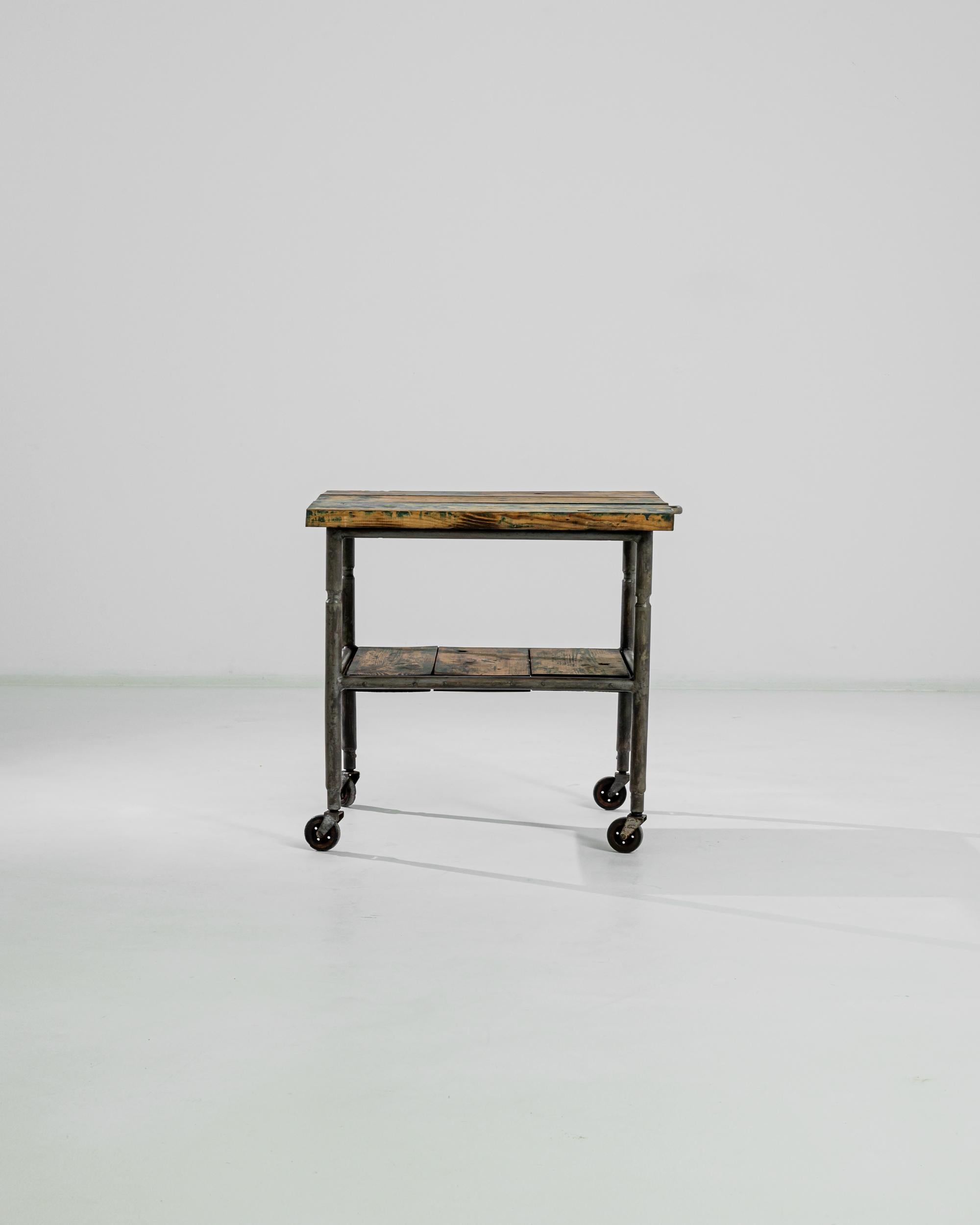Retired from industrial use, this sturdy cart was sourced in Central Europe. Metal rods, welded and bolted, snap together to construct this perky rolling cart. A time-altered, patinated wood top invites the accompaniment of refined homegoods. Simple