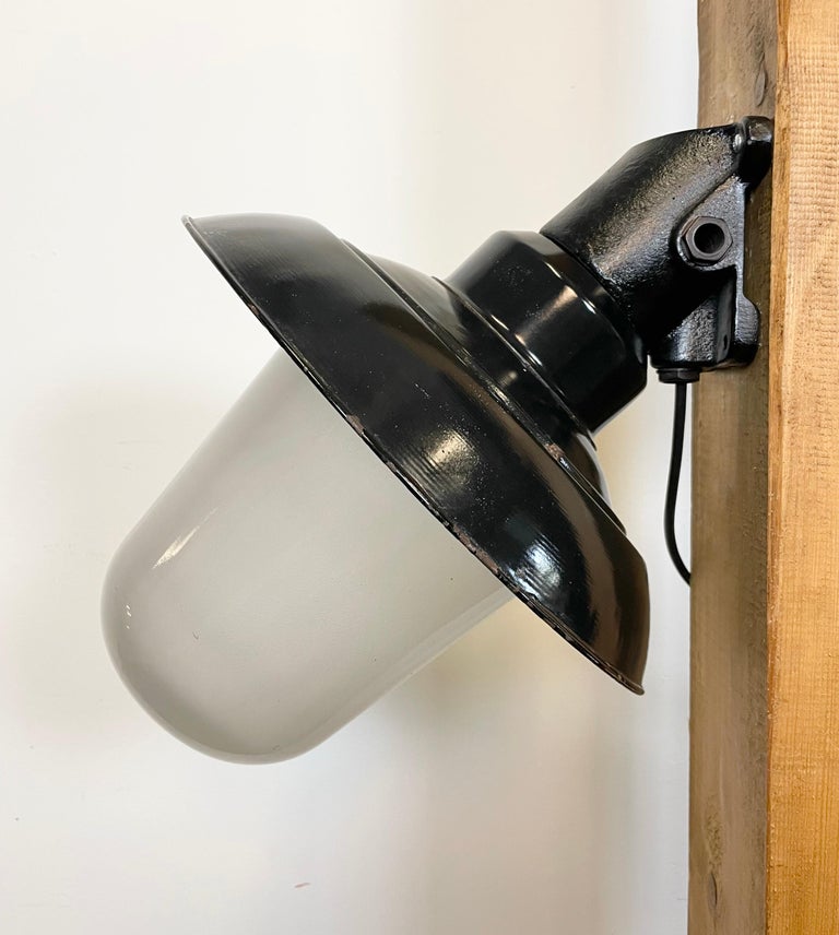 - Industrial wall lamp with cast iron wall mouting from former Czechoslovakia made during the 1960s
- Black enamel shade with white enamel interior, milk glass
- New porcelain socket for E 27 light bulbs and wire
- Weight: 5 kg.
