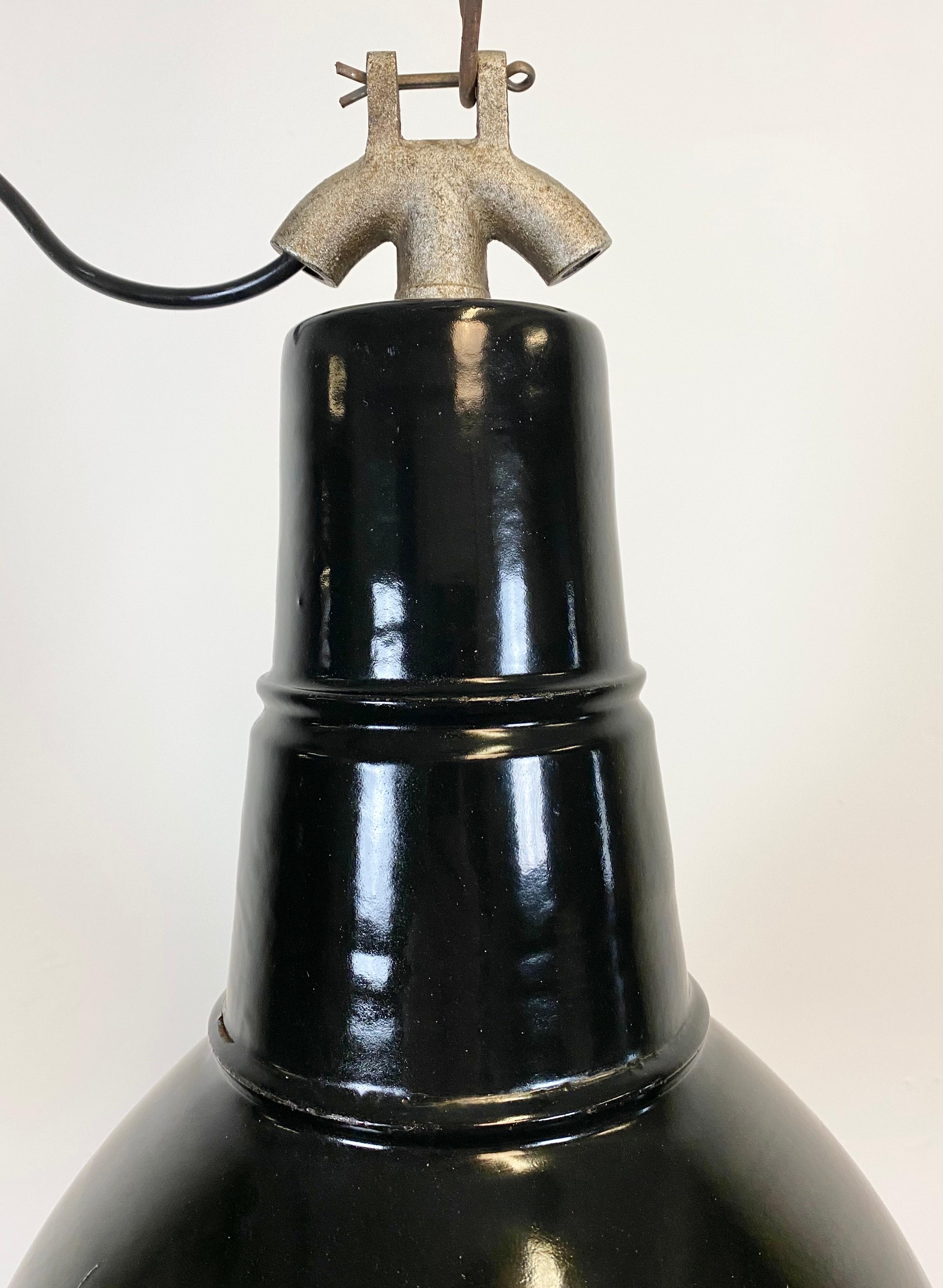 This vintage industrial black enamel pendant lamp in Bauhaus style was used in factories in the former Czechoslovakia during the 1930s. It has a white enamel interior and an interesting cast iron top. It features a new porcelain socket for E 27