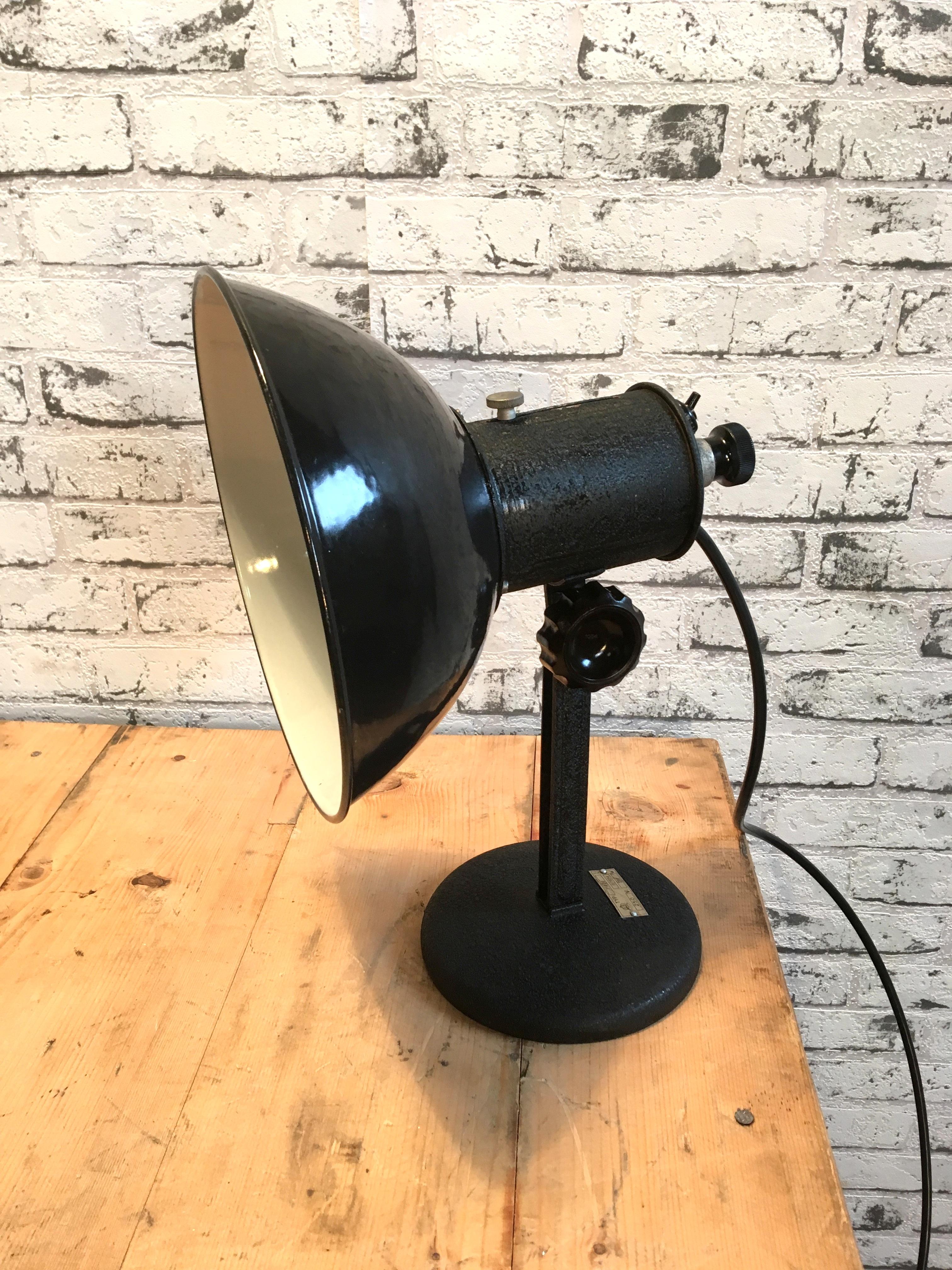 Industrial table lamp from former Czechoslovakia made during the 1950s. Black enamel shade, white interior. Porcelain socket for E 27 lightbulbs, new wire. Very good vintage condition. Fully functional.
 