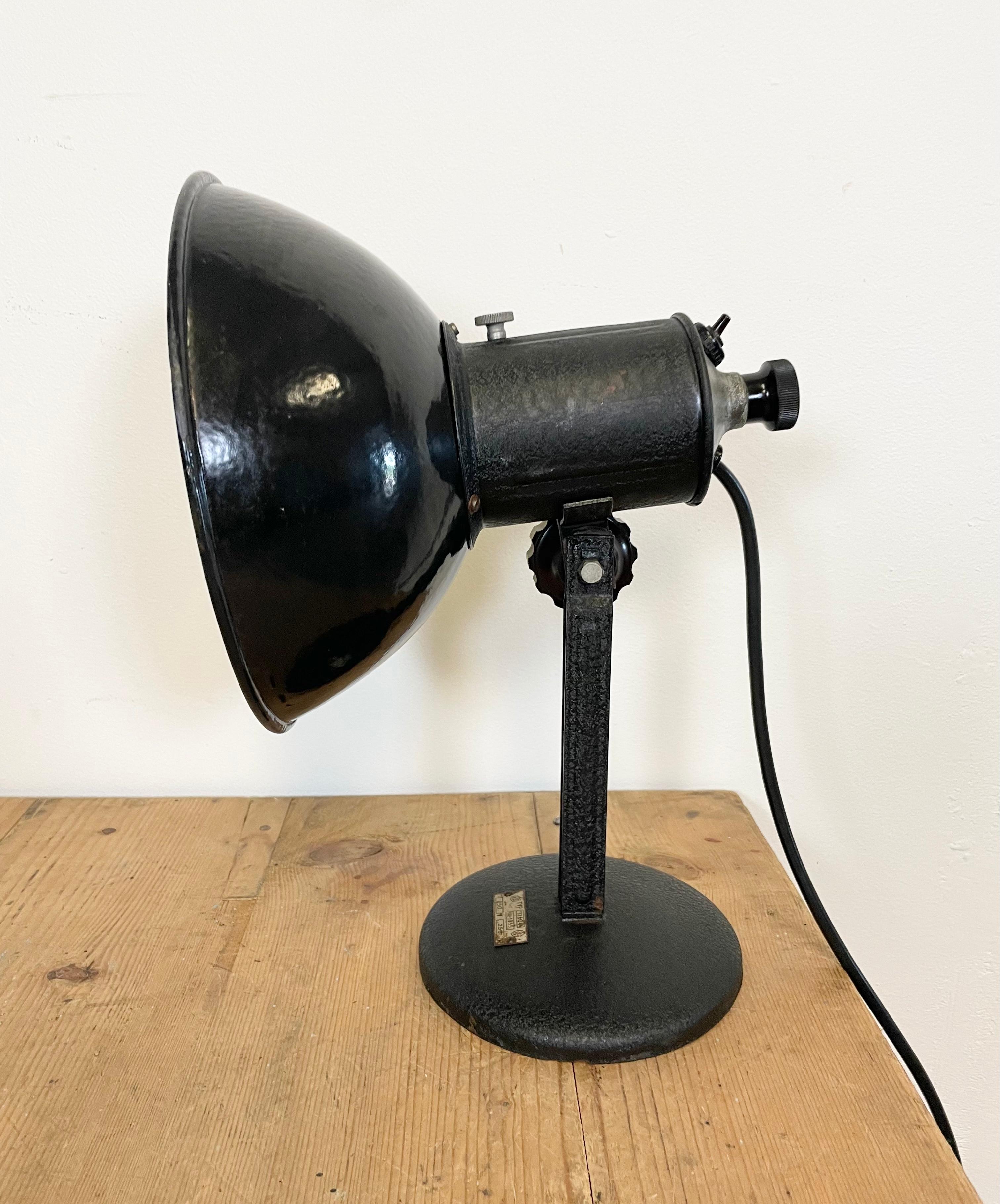 Industrial adjustable table lamp from former Czechoslovakia made during the 1950s. It features a black enamel shade with white enamel interior an iron base. Porcelain socket for E 27 lightbulbs, new wire. Very good vintage condition. Fully