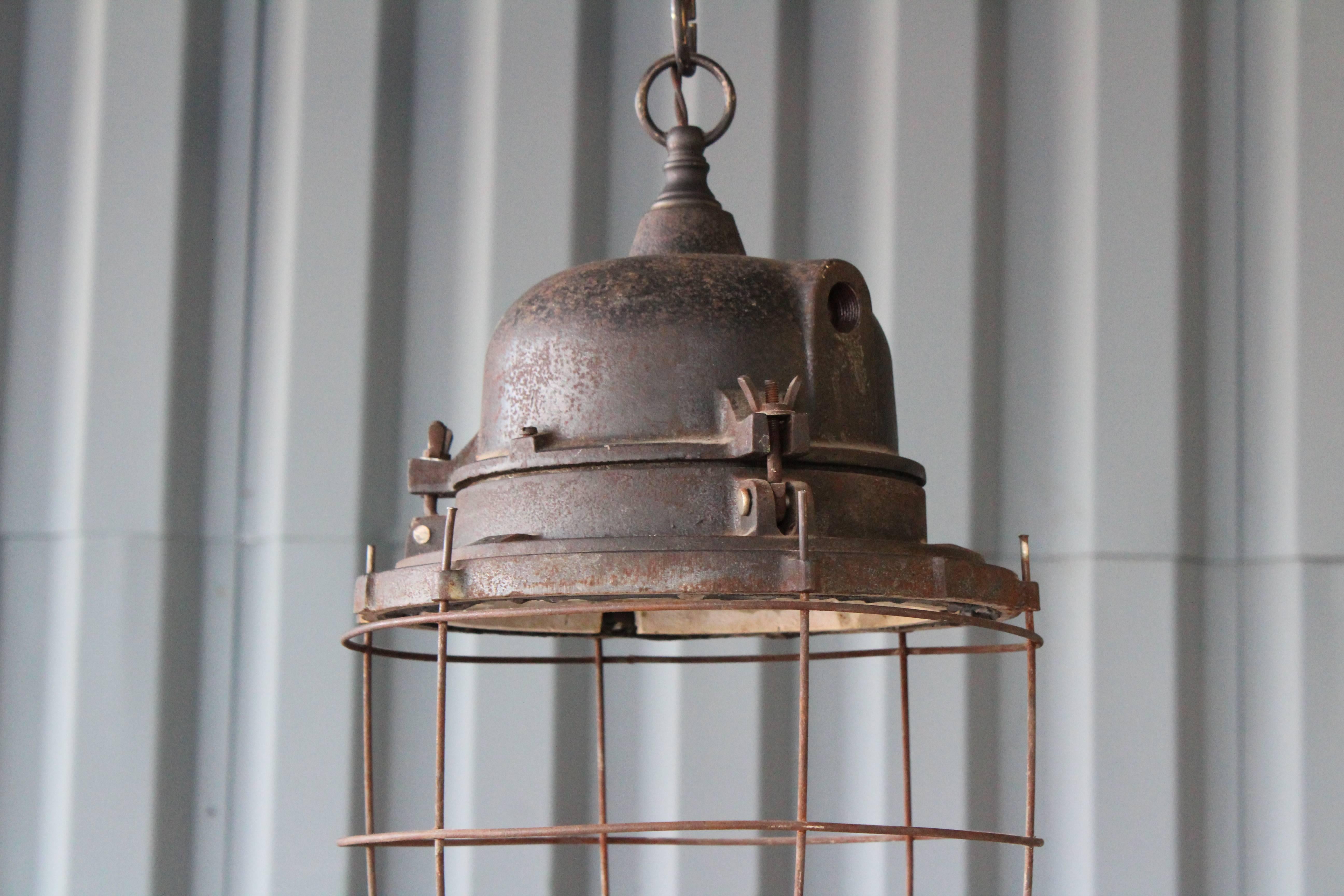 Vintage industrial hanging light with metal cage cover. Newly rewired.