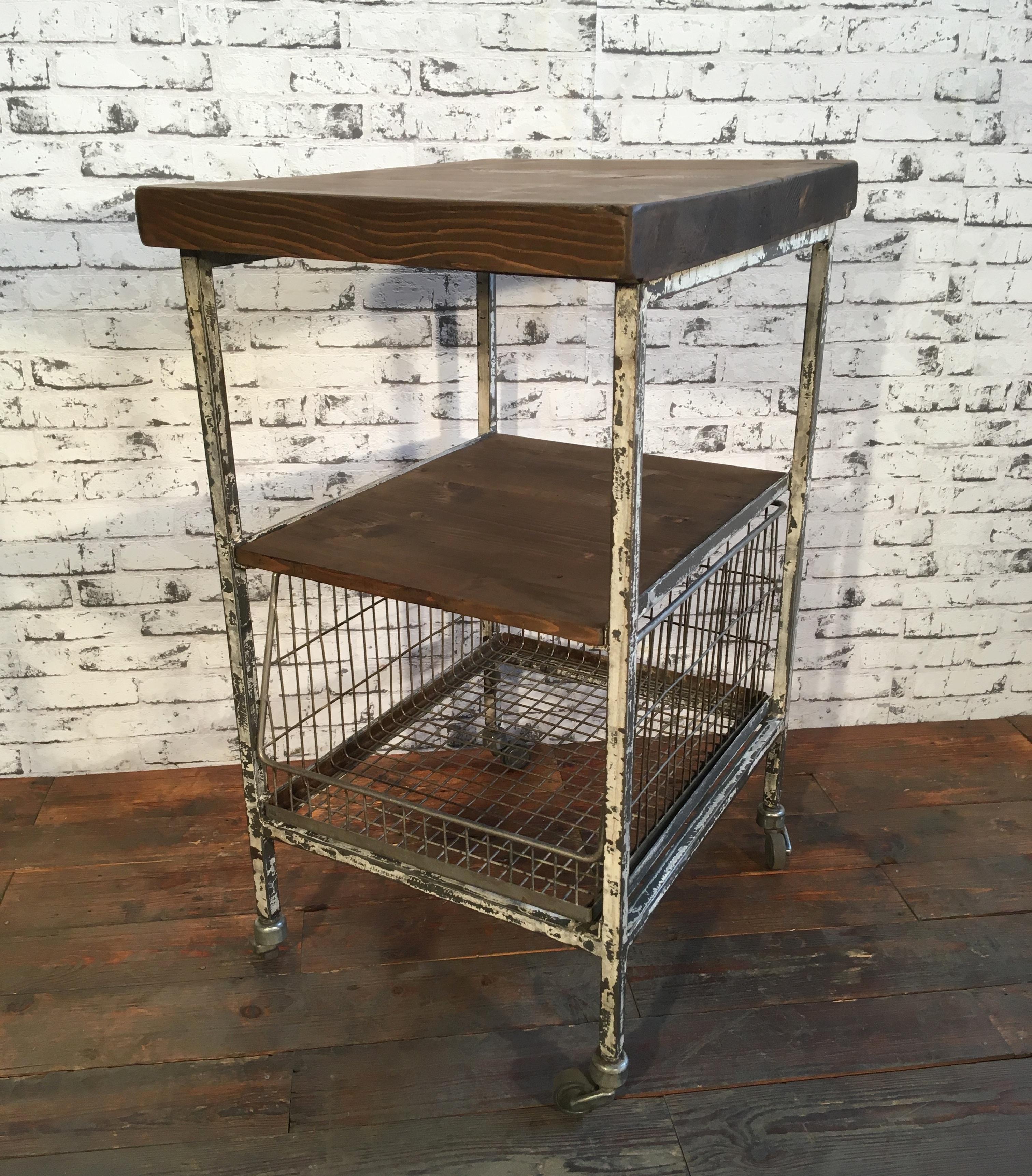 Industrial trolley with shelves.It features iron construction with four wheels and three shelves. Two shelves are wooden one forms a wire basket. Good vintage condition. Weight: 23 kg.