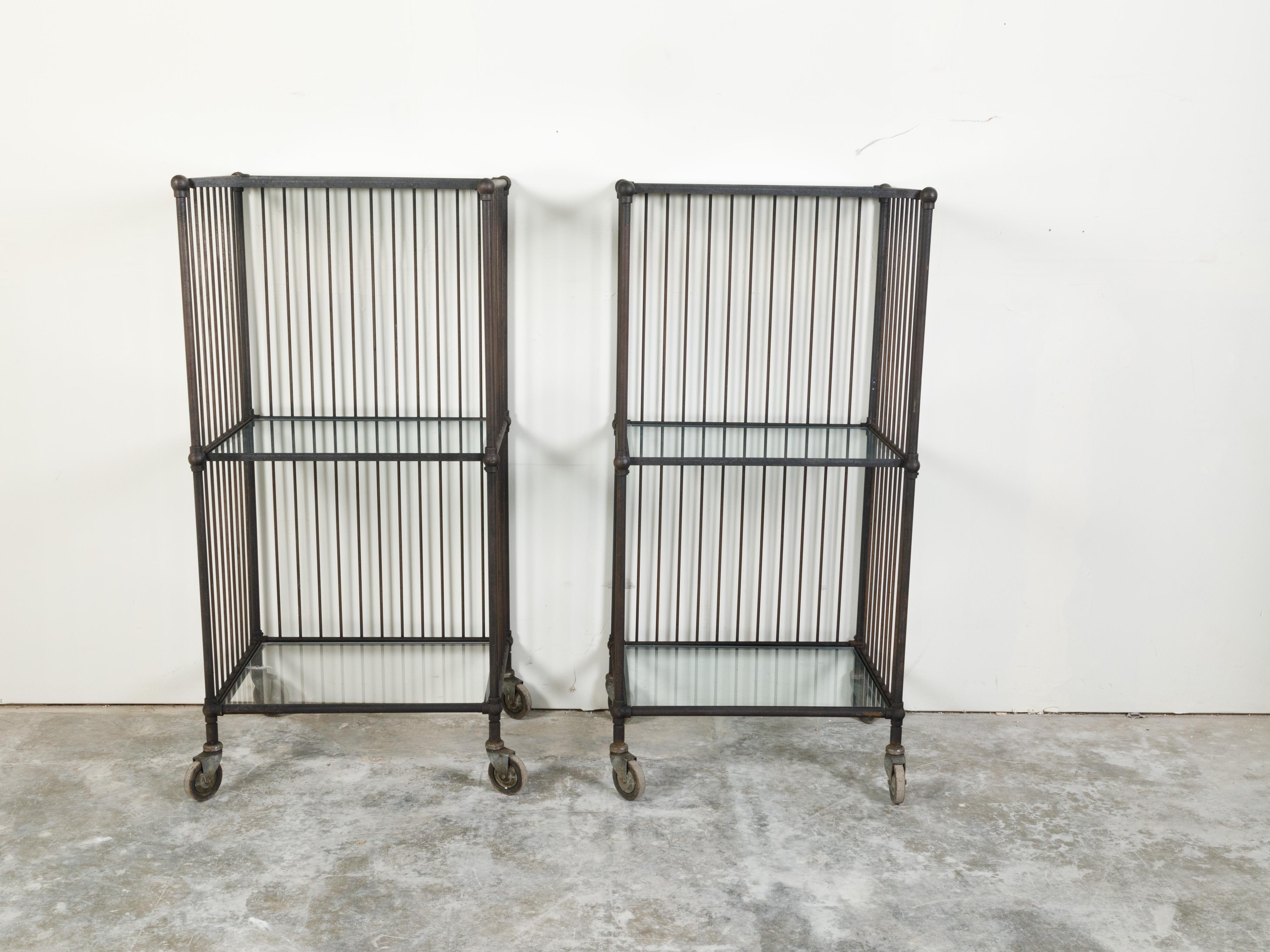 Two vintage industrial carts from the 20th century, with glass shelves and casters, priced and sold $5,400 each. Created during the 20th century, each of this pair of carts captures our attention with their clean lines and industrial look. Each