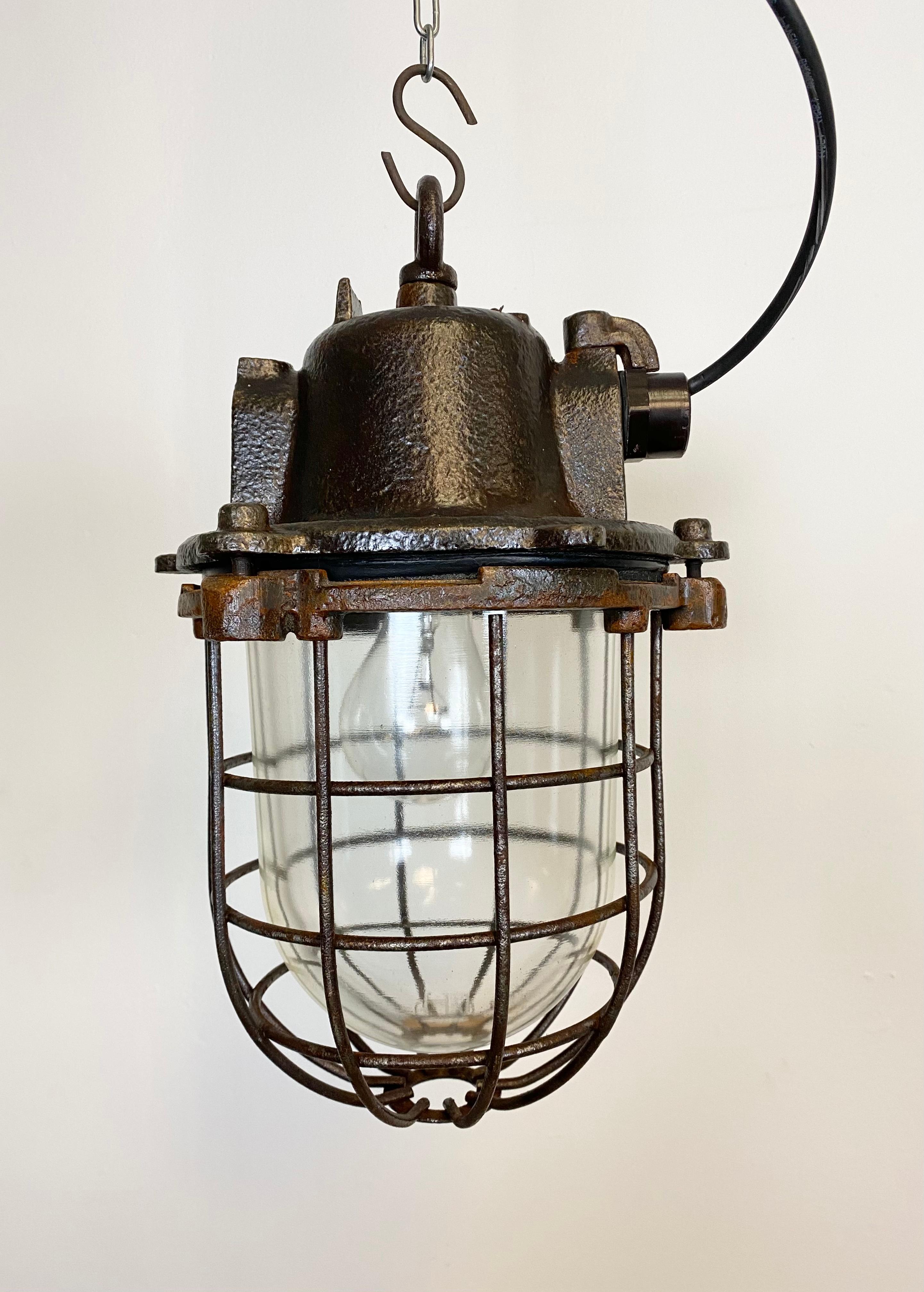Industrial hanging lamp made in former Czechoslovakia during the 1960s. It features cast iron top, clear glass cover and iron grid. Porcelain socket for E 27 lightbulbs and new wire. The weight of the lamp is 9 kg.