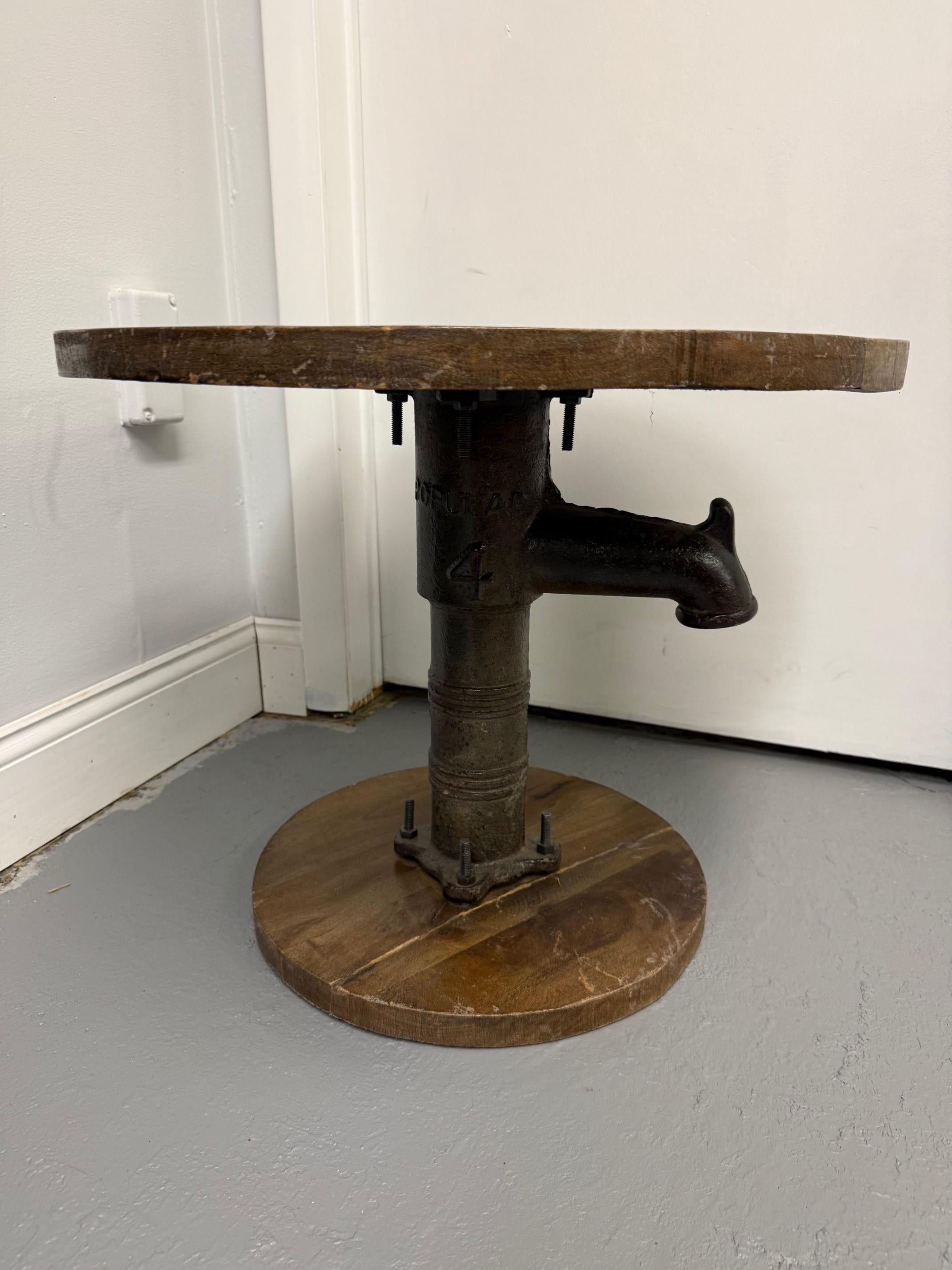 Vintage Industrial Chic Iron & Wood Water Pump Side Table. This is a unique piece imported from India in the late 1990s and is made with an antique iron water pump with a hardwood top and base. It's a great industrial piece with original markings on