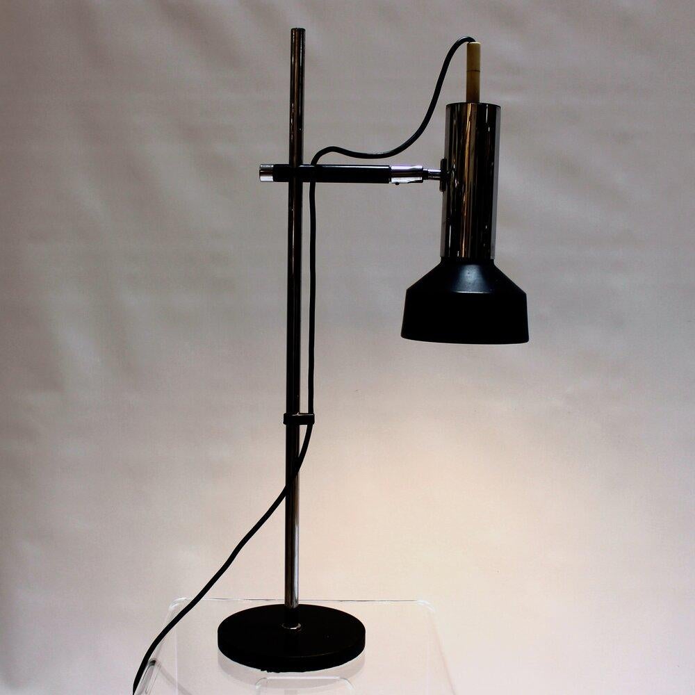 Vintage industrial design chrome and black articulating desk lamp. Lamp height is adjustable and the head pivots. Very striking vintage industrial design, with an almost Bauhaus sensibility. In-line switch.

Measures: width: 13 in / depth: 7 in /