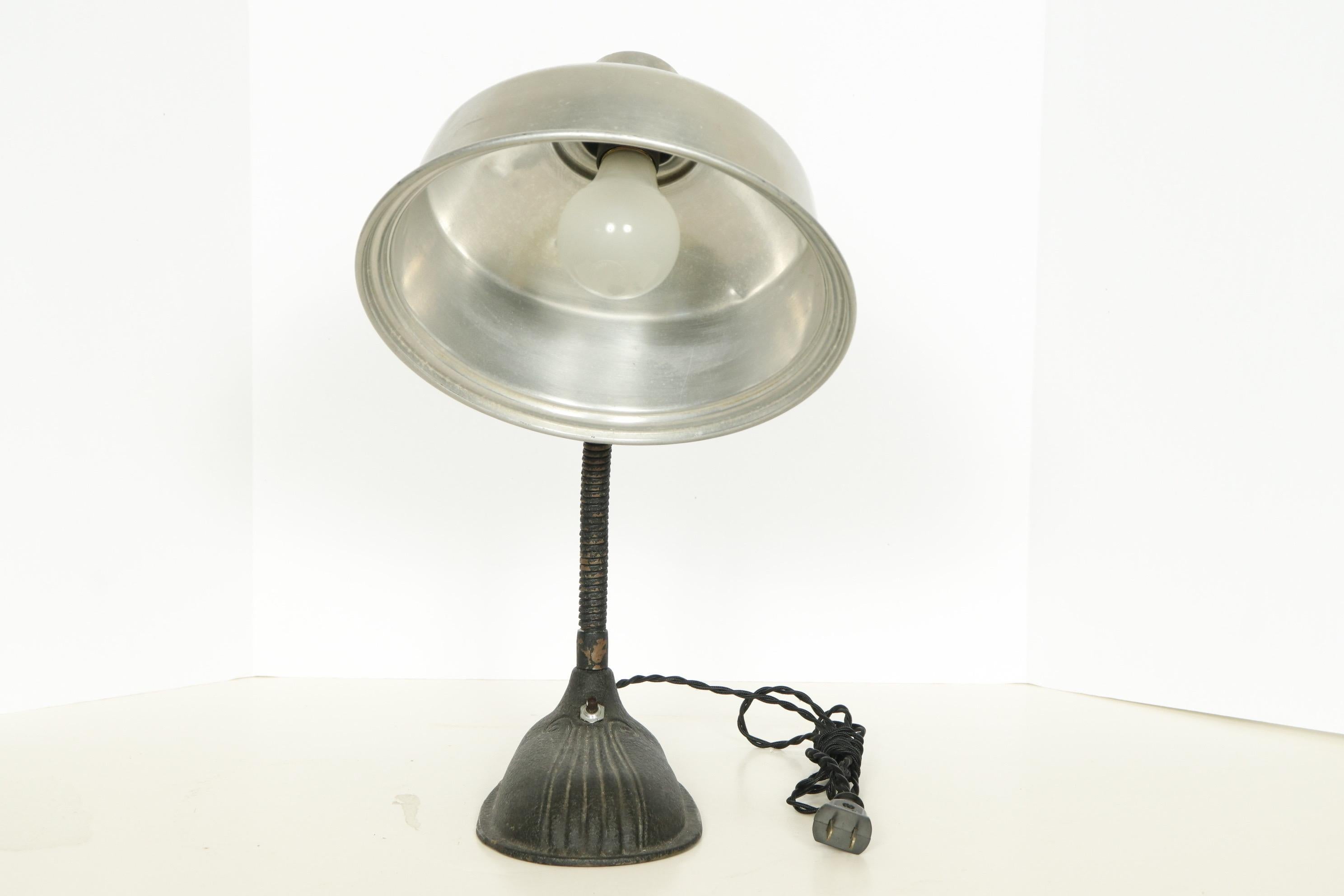 Antique industrial task lamp with an aluminum shade and black cast iron base.

USA, 1920-1930.

Features:
*Rewired with French silk twist cord
*Takes standard bulb, 60 watts max

Dimensions: 16” H x 13” L x 4.75” D.