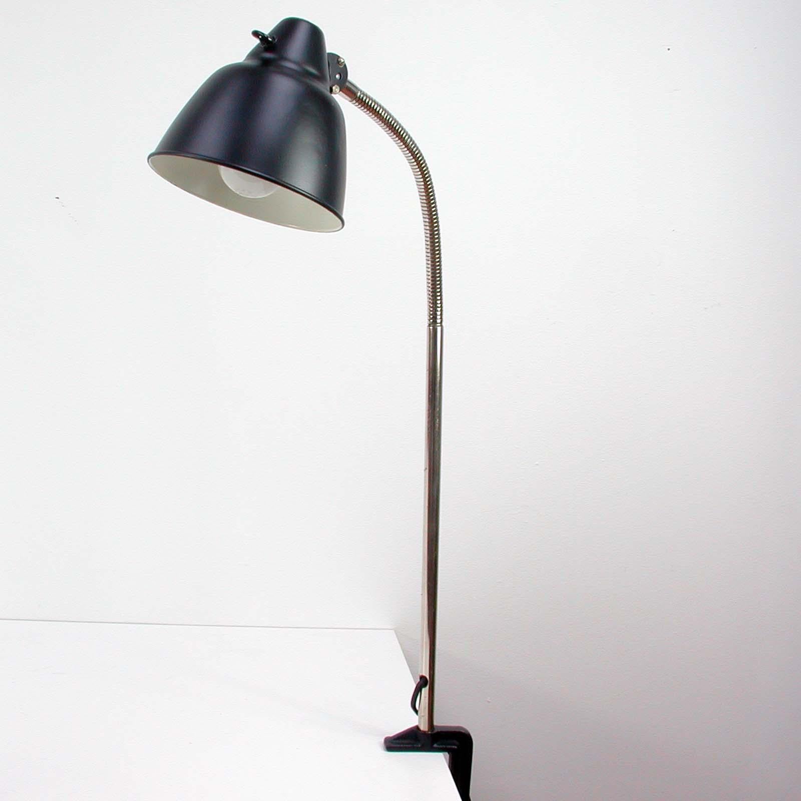 This vintage desk light was designed and manufactured by HELO in Neuburg in the 1950s.

The lamp features an aluminum lampshade and a flexible, chrome-plated gooseneck lamp arm. The bakelite on/off switch is located on the lampshade. The base of the