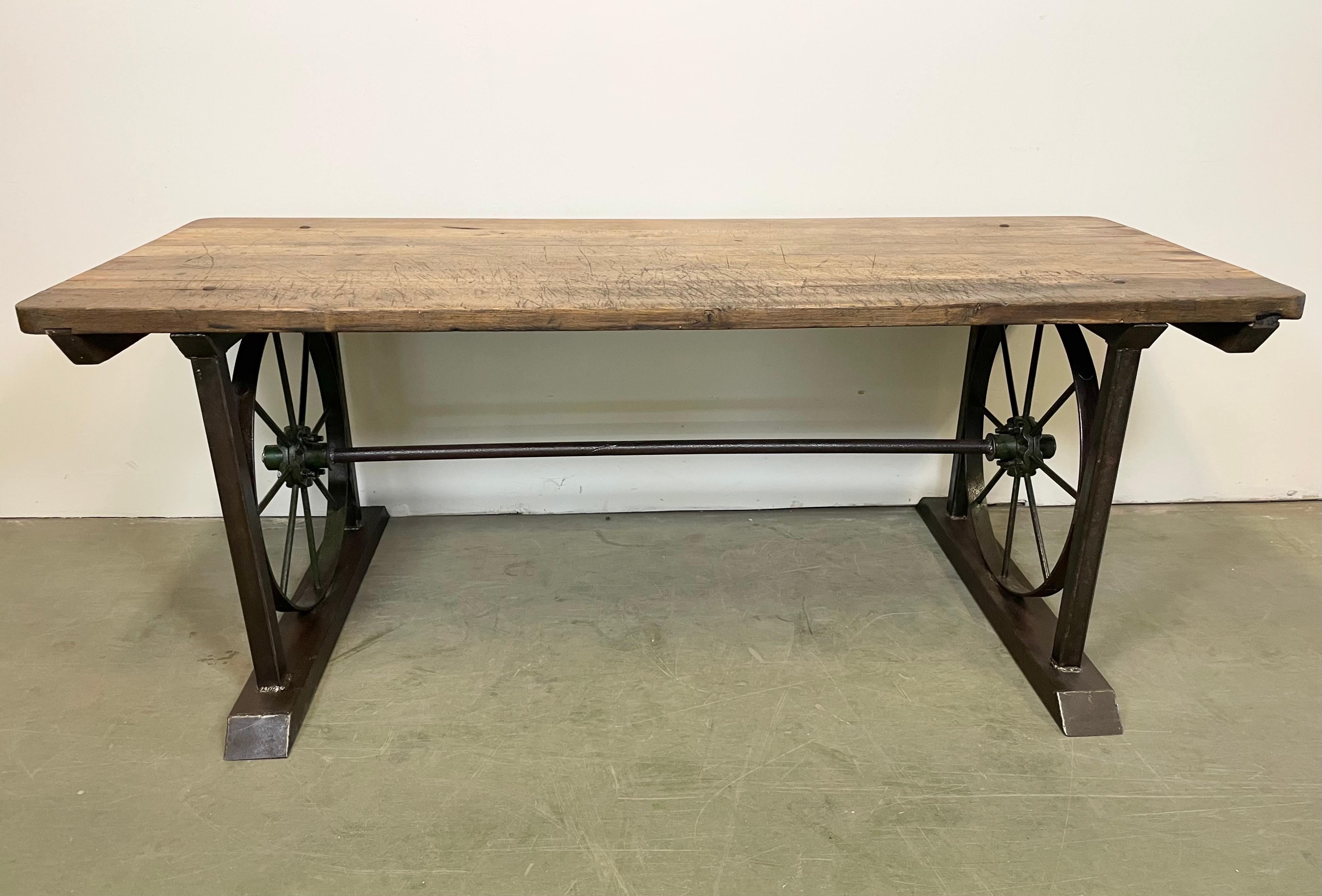 Industrial dining table made during the 1950s. It features a cast iron construction and an oak wooden plate. The weight of the table is 100 kg.