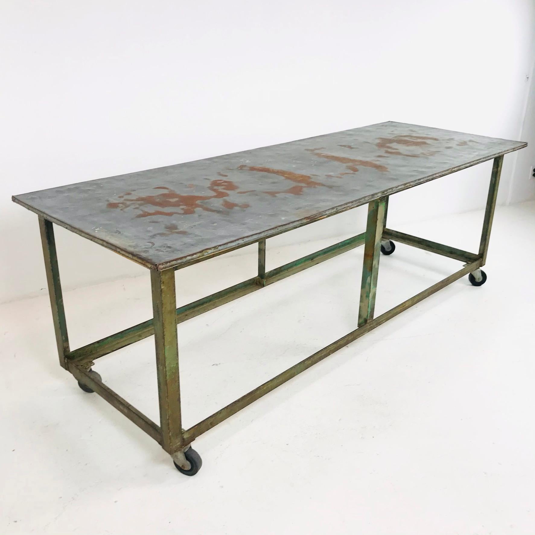 Robust, vintage American industrial four-legged display/work table on casters.