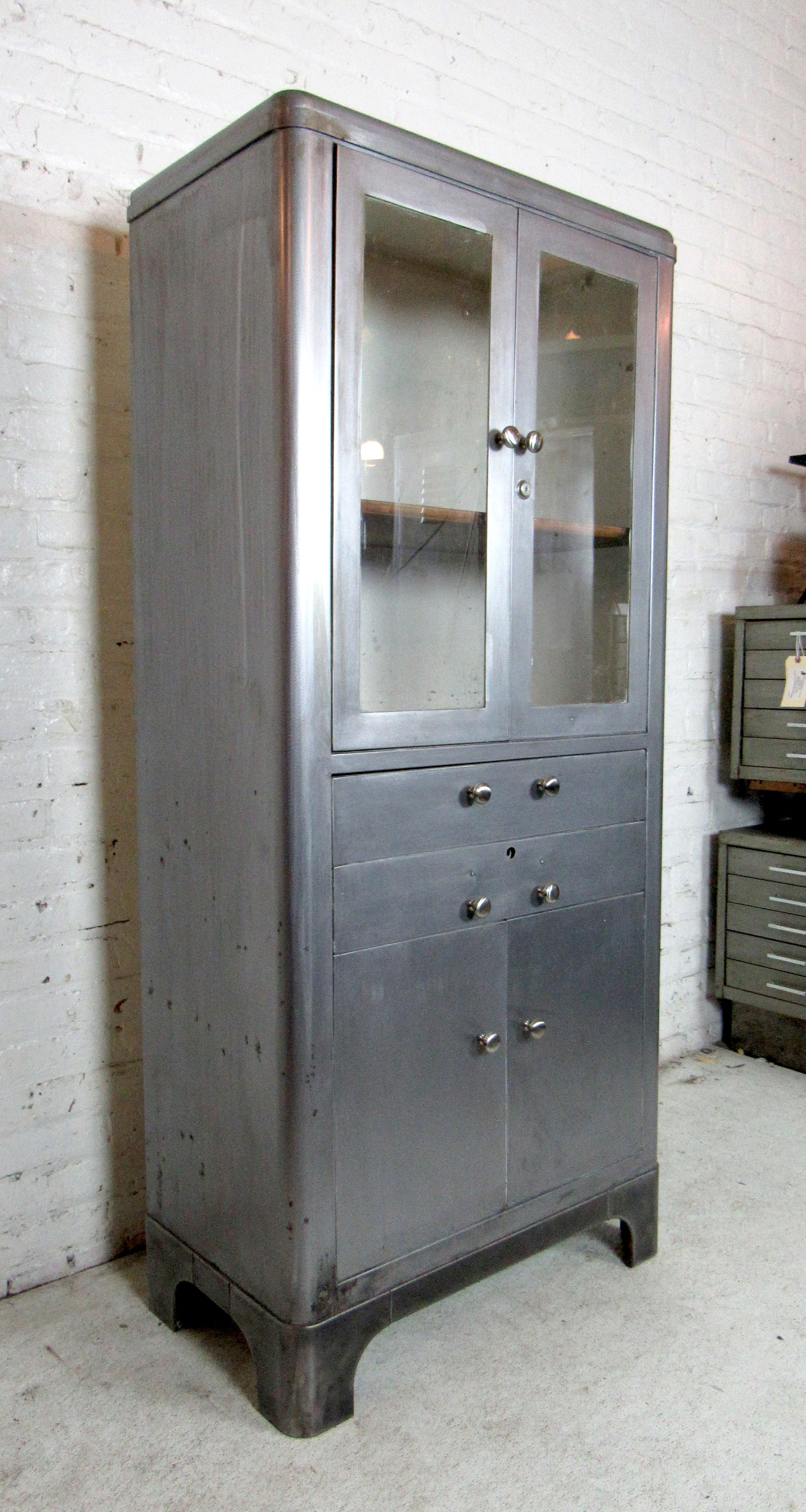 Vintage metal Doctor's cabinet, refinished in an industrial finish. Striking bare metal finish with glass windows and a wooden shelf.

(Please confirm item location - NY or NJ - with dealer).