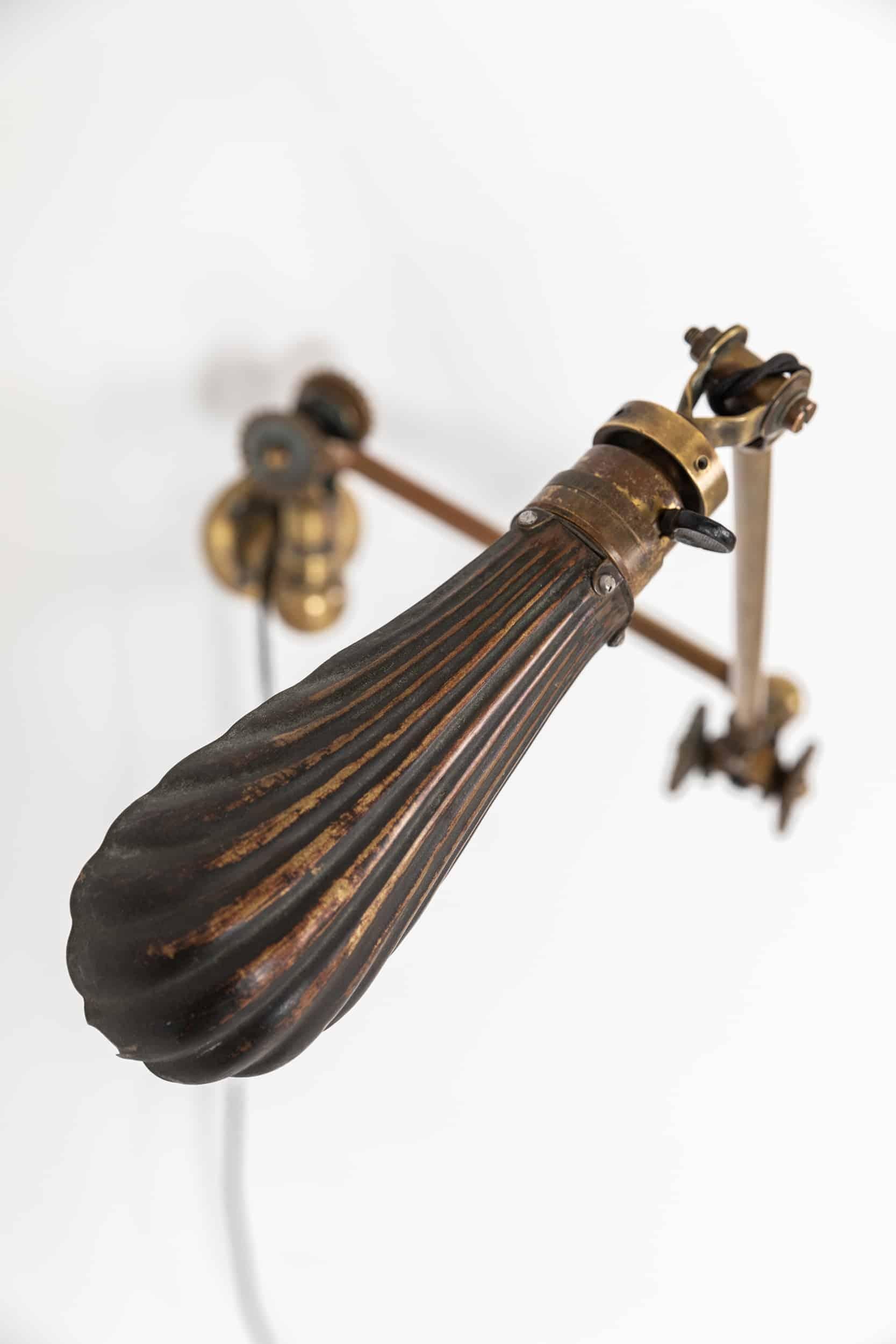 A stunning wall lamp by renowned English lighting company Dugdills. c.1920

This example, made entirely of brass, features the earlier 'rosettes' or daisy wheels for adjusting and tightening the joints into position and elongated shell