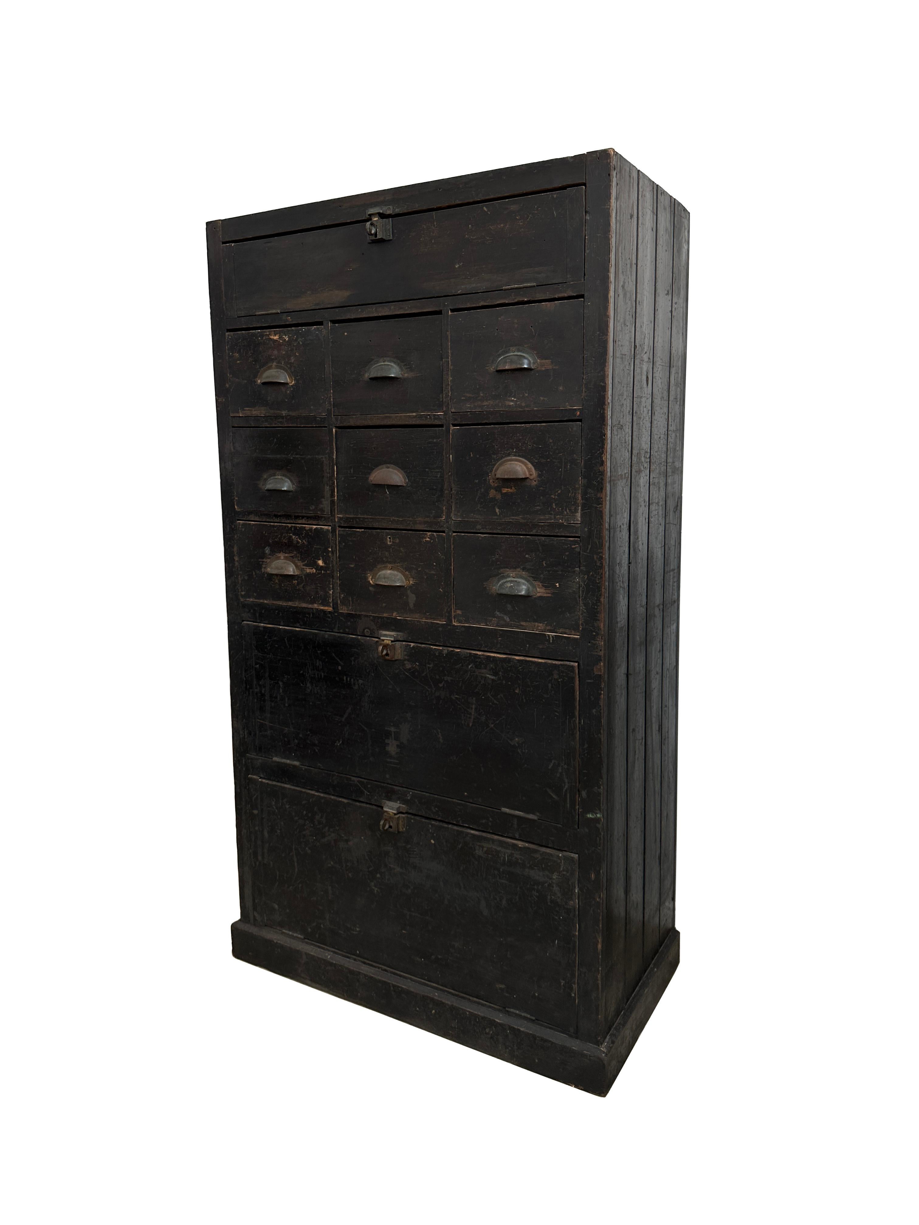 - A beautiful bank of industrial ebonised pine workshop drawers of large proportion, circa 1930.
- There are nine drawers in total, all tongue and groove in construction and across the middle section, and then three most unusual drop down drawers