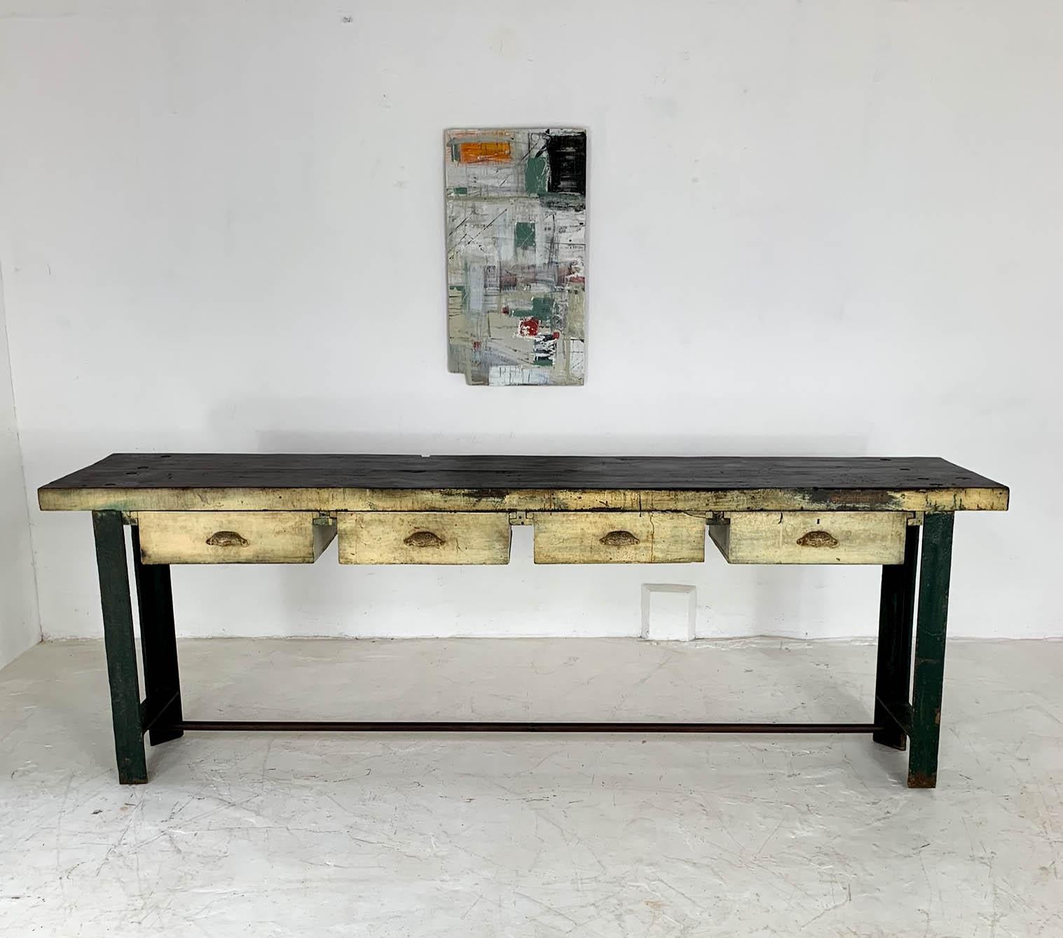 Fantastic, all original engineer's workbench sourced from Staffordshire, England. We love the elegant shape of the green cast iron ends, set against the dark stained and varnished chunky top; complemented by four creamy yellow colored drawers with