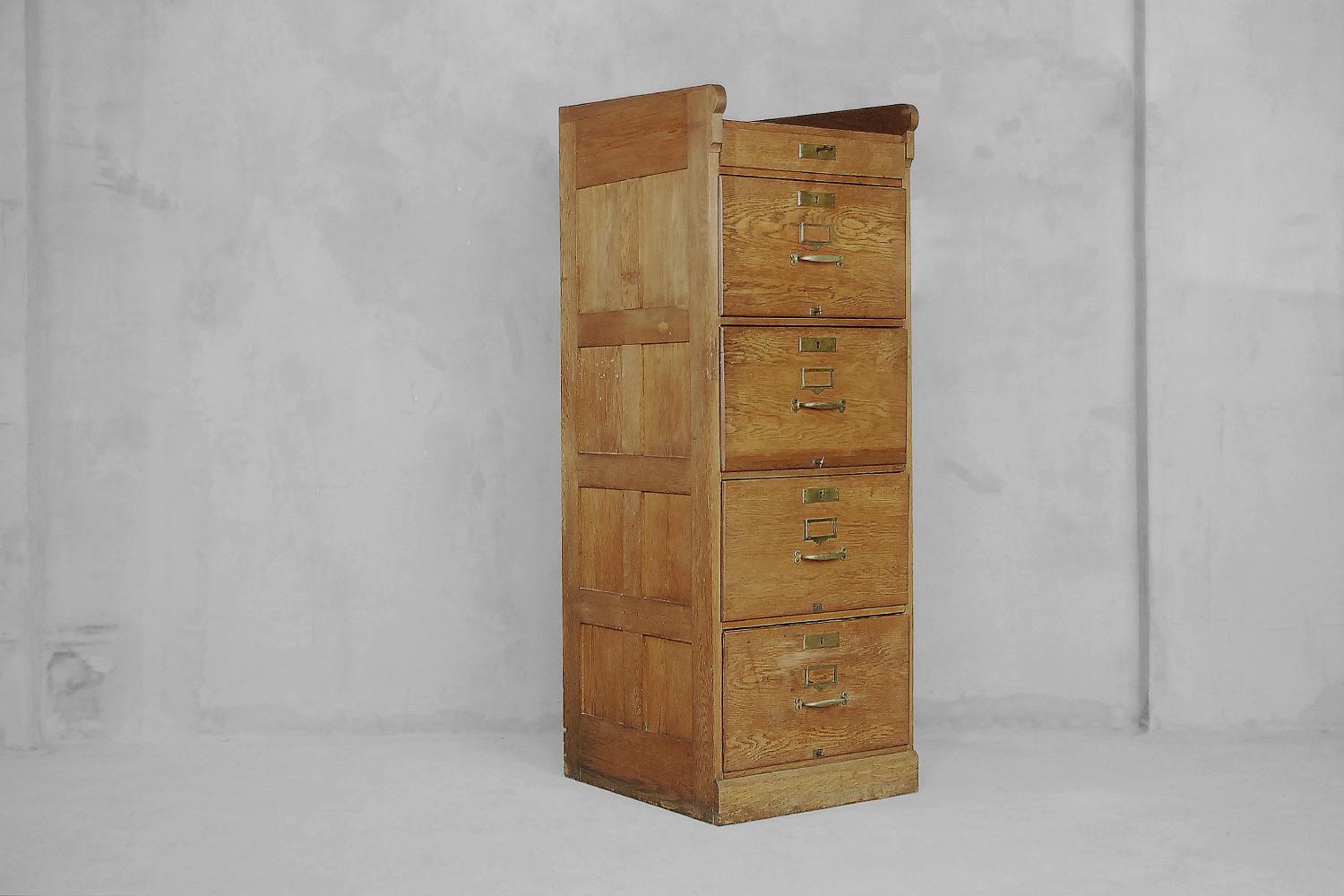 This antique cabinet was manufactured in England in first half of the 20th century. It is made from solid oak wood. It has four deep drawers with compartments and one smaller under the top. The drawers have a file system and handles in brass. One
