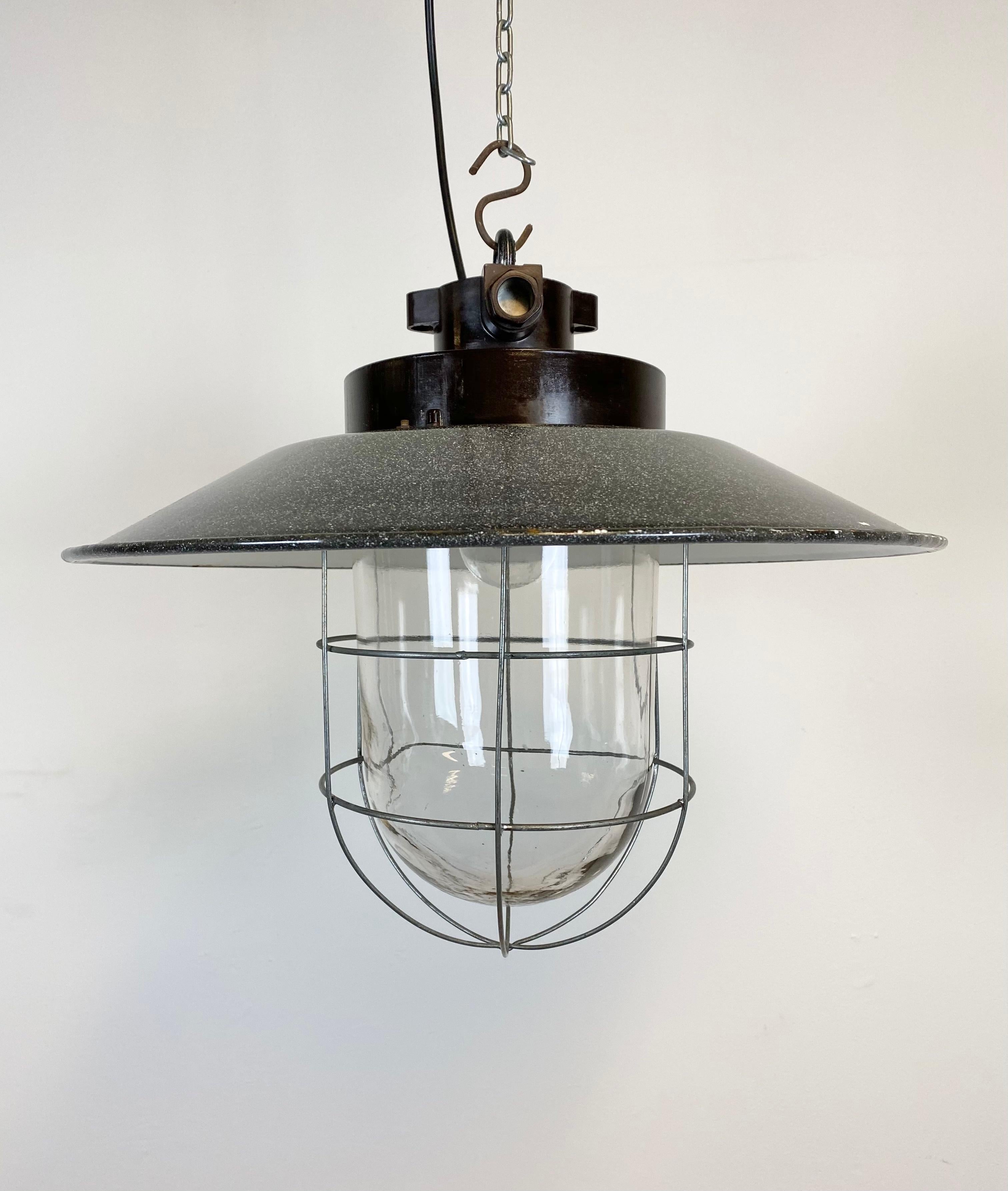 - Vintage industrial lamp from former Czechoslovakia made during the 1960s
- Grey enamel shade with white interior
- Bakelite top
- Clear glass, iron grid
- Porcelain socket for E 27 lightbulbs
- New wire
- Weight: 3.5 kg.
  