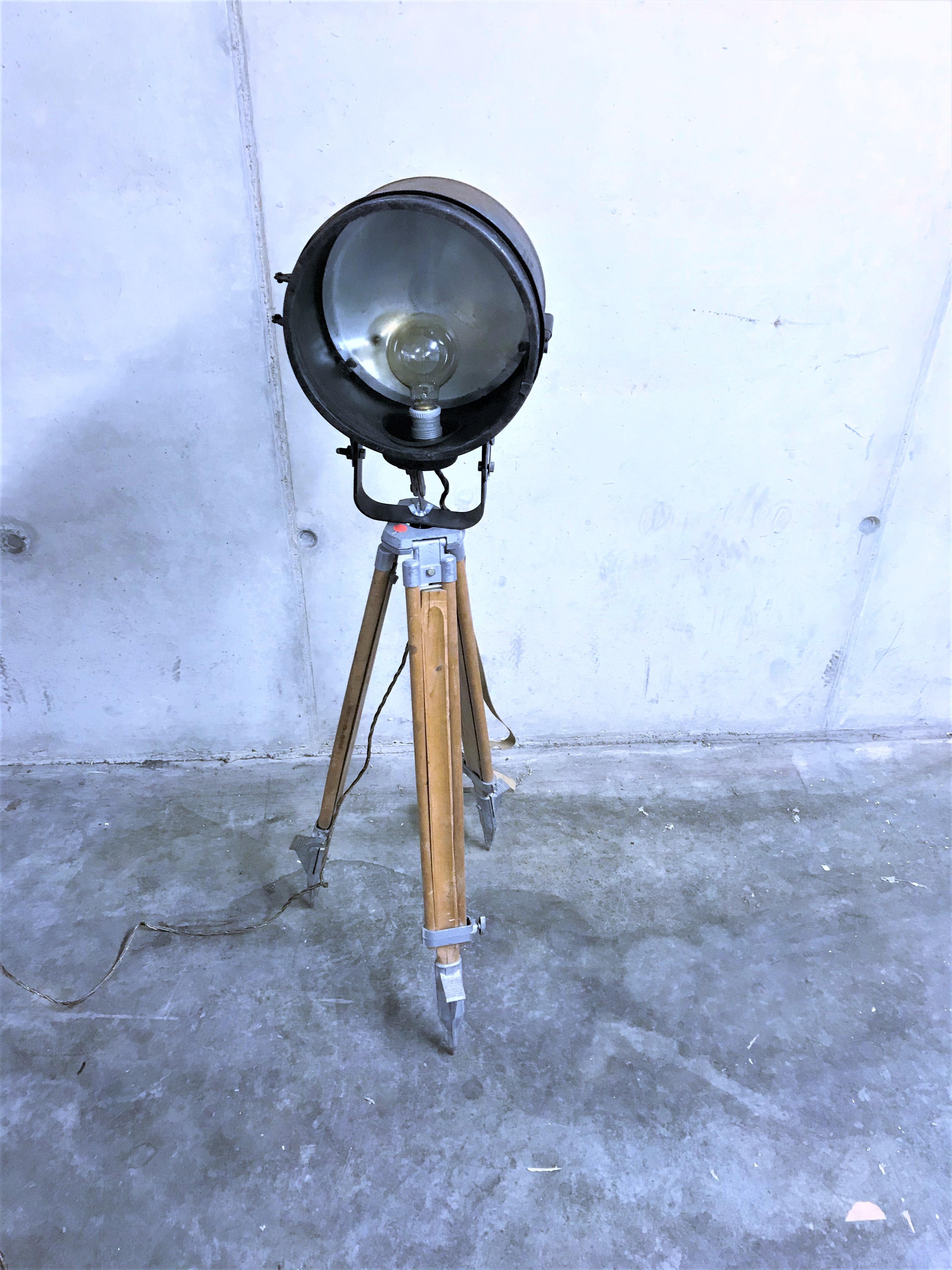 Beautiful original, 1970s Industrial tripod floor lamp.

The lamp consists of an in height adjustable wooden tripod base from a russian military stock.

The lamp was salvaged from a military boat in latvia and is dated 1973.

Both tripod and