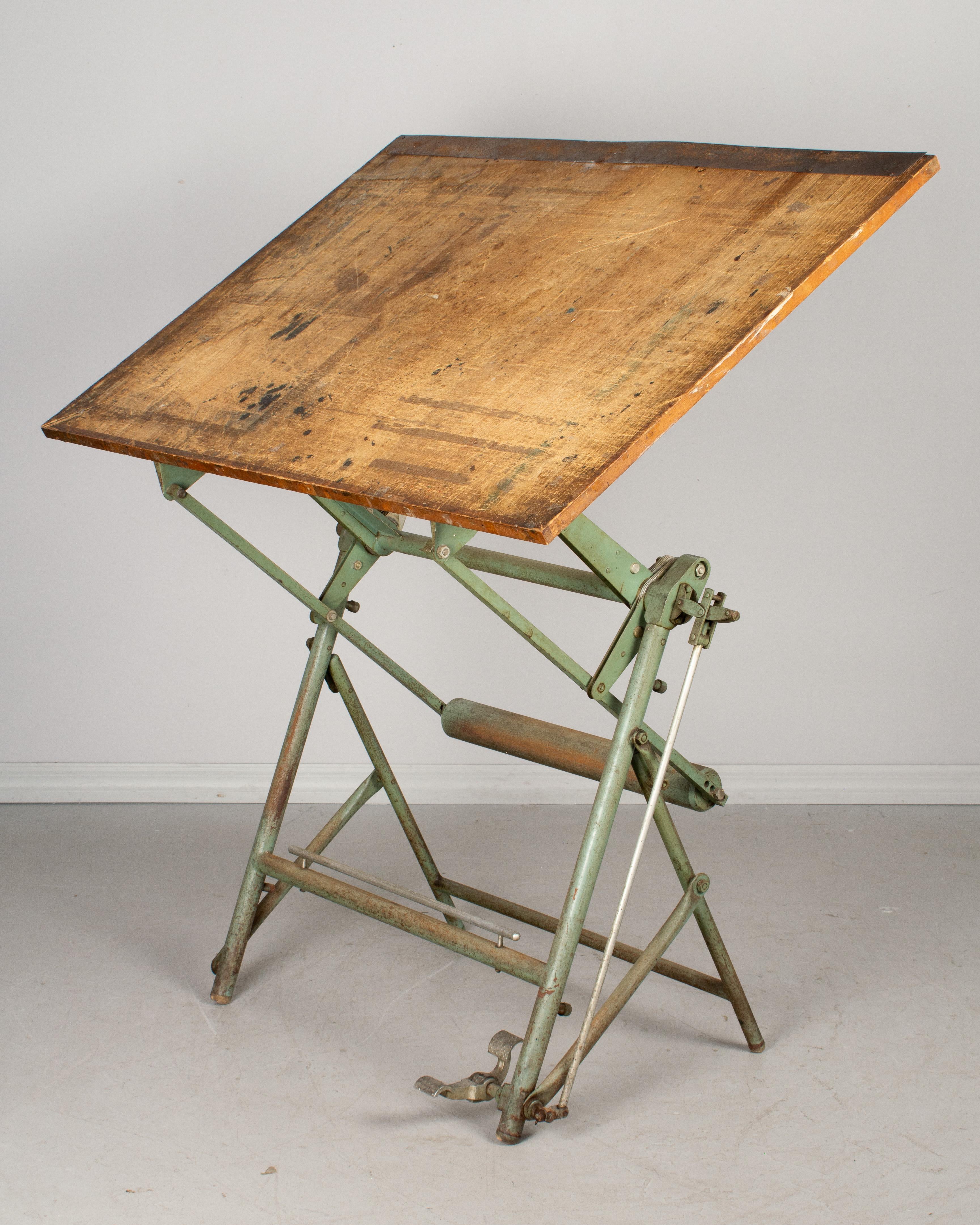 A French Industrial style mechanical architect's drafting table with original green lacquered metal base and large solid wood top. The platform is fully modular: using a pedal on the right it is possible to raise and lower the top and tilt it to any