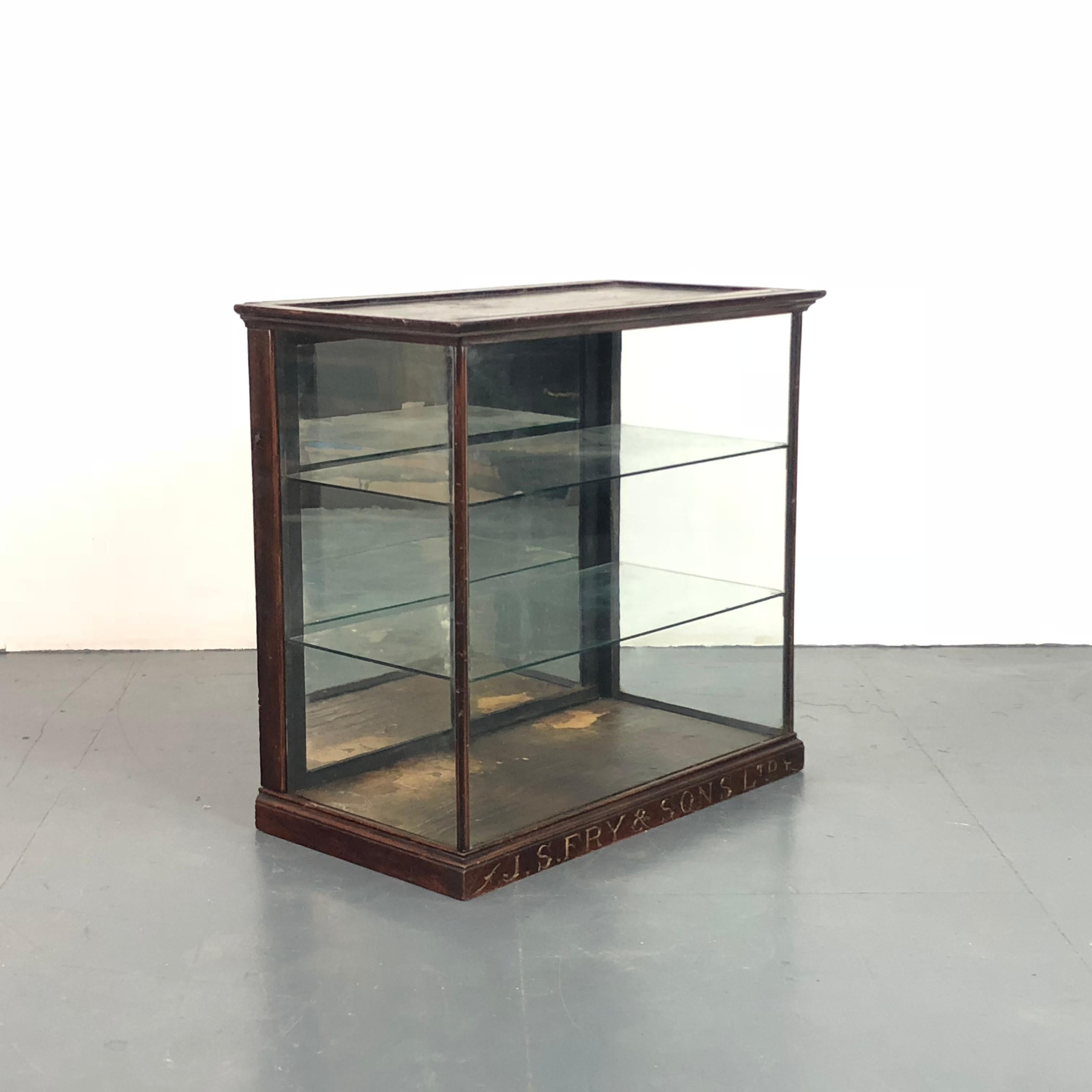 Wonderful glazed JS Fry & Sons display cabinet from the late 19th/early 20th century. This is a counter top piece. The interior is accessed through mirrored sliding doors on the back. It stands on a small engraved plinth and has two glass