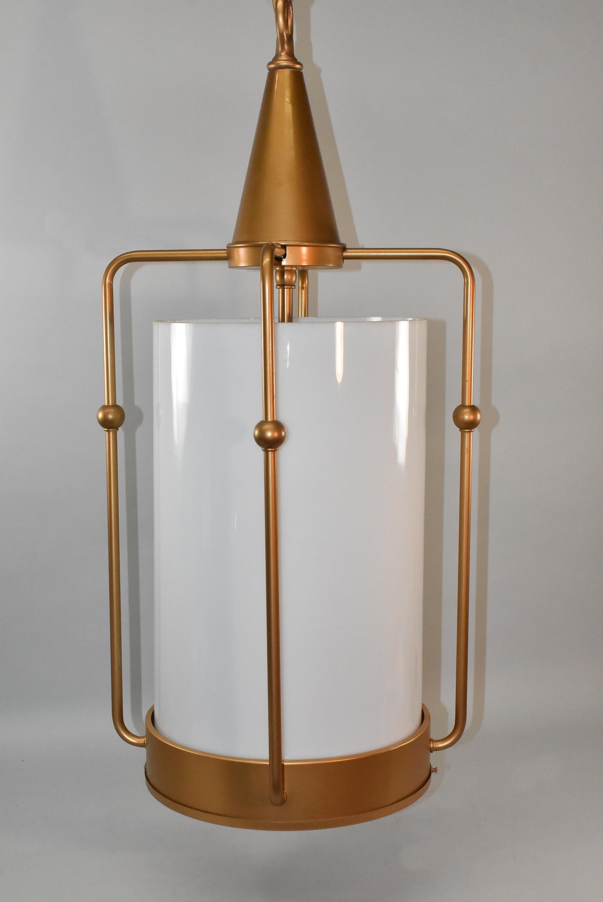 Industrial vintage gold and opaque white glass cylinder column chandelier /pendant. Gold cage shape open frame with cone shape top and gold decorative details. Four interior sockets. Three fixtures are available. Price reflects one.