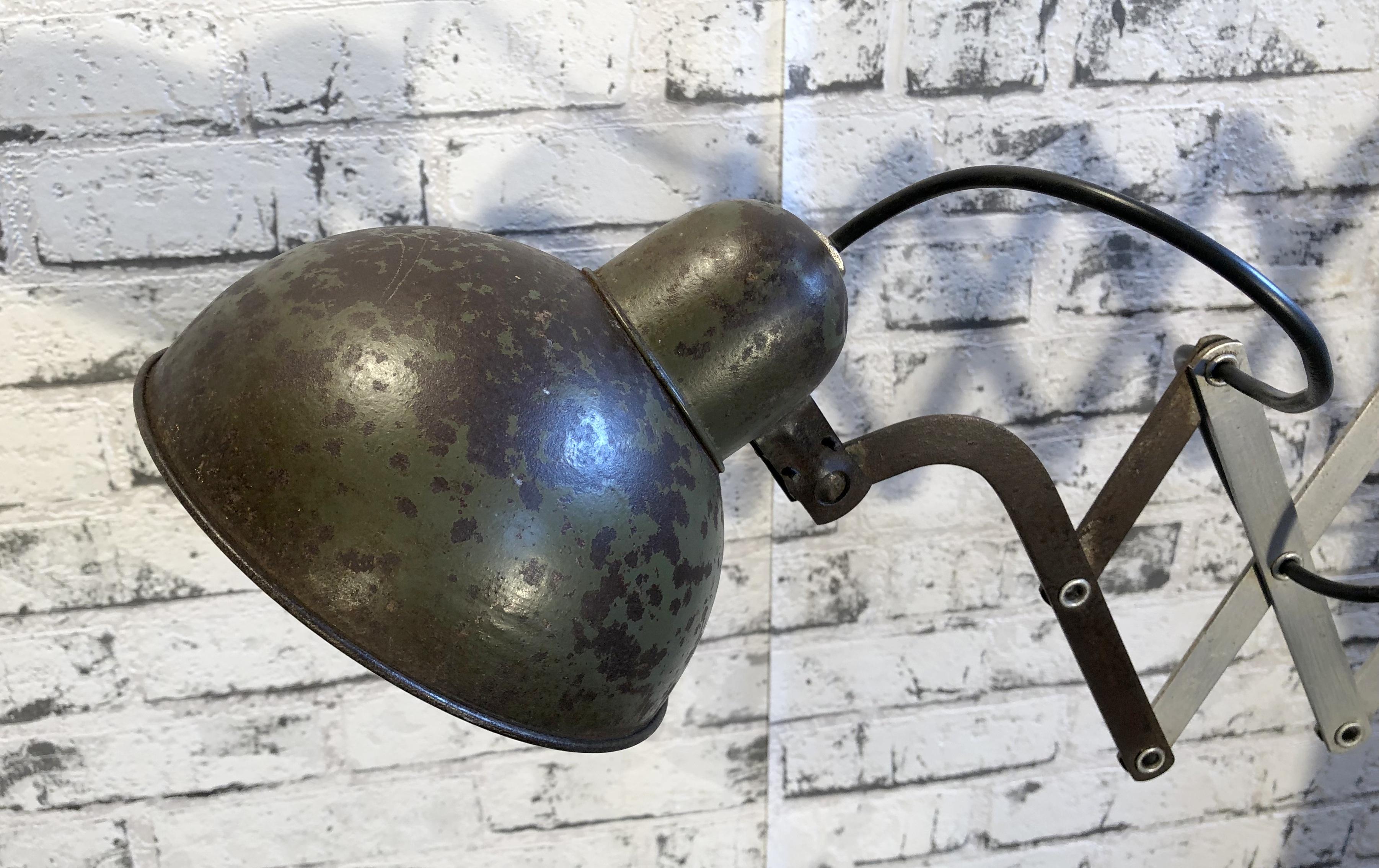 This vintage Industrial scissor lamp was produced in former Czechoslovakia during the 1960s. The lamp has a beige metal shade. The iron scissor arm is extendable and can be turned sideways. New porcelain socket for E 27 lightbulbs. Lampshade
