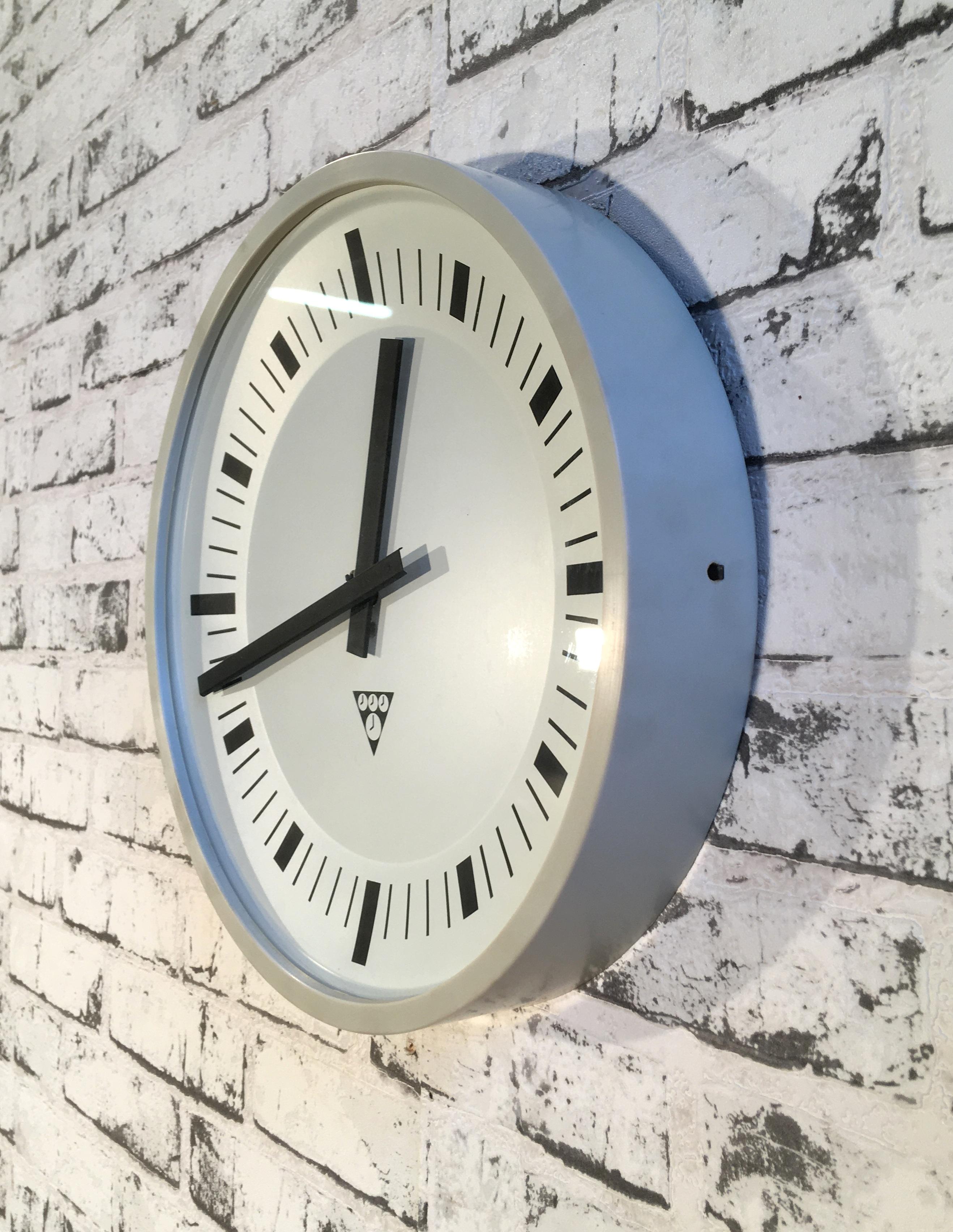 This wall clock was produced by Pragotron in former Czechoslovakia during the 1970s. It features a grey bakelite frame and a clear glass cover. The piece has been converted into a battery-powered clockwork and requires only one AA-battery.