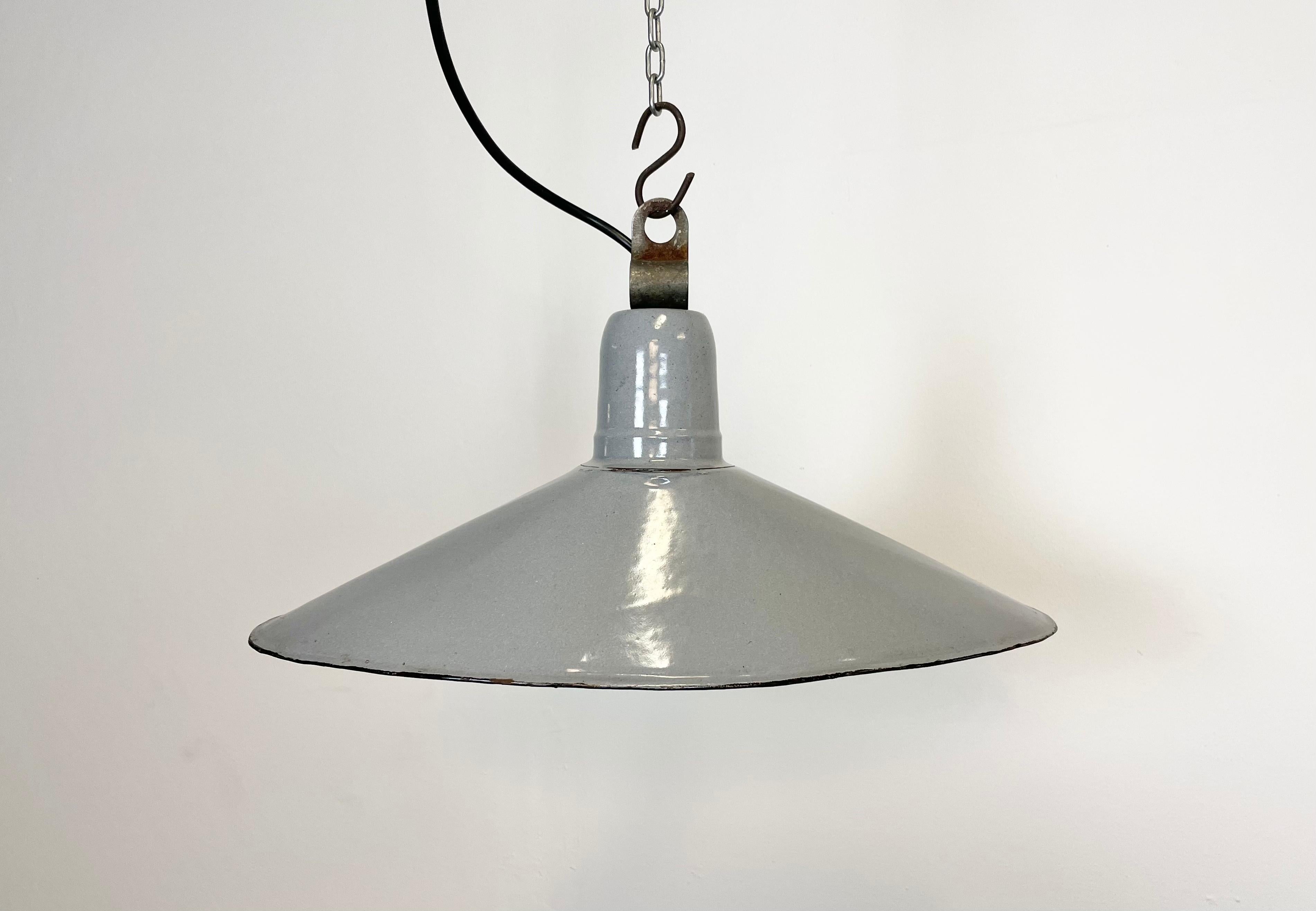 Vintage industrial grey enamel pendant lamp from the 1930s. It features a grey enamel shade with white enamel interior and iron top. Original porcelain socket requires E 27 light bulbs. New wire. Unusual shape of the lampshade.