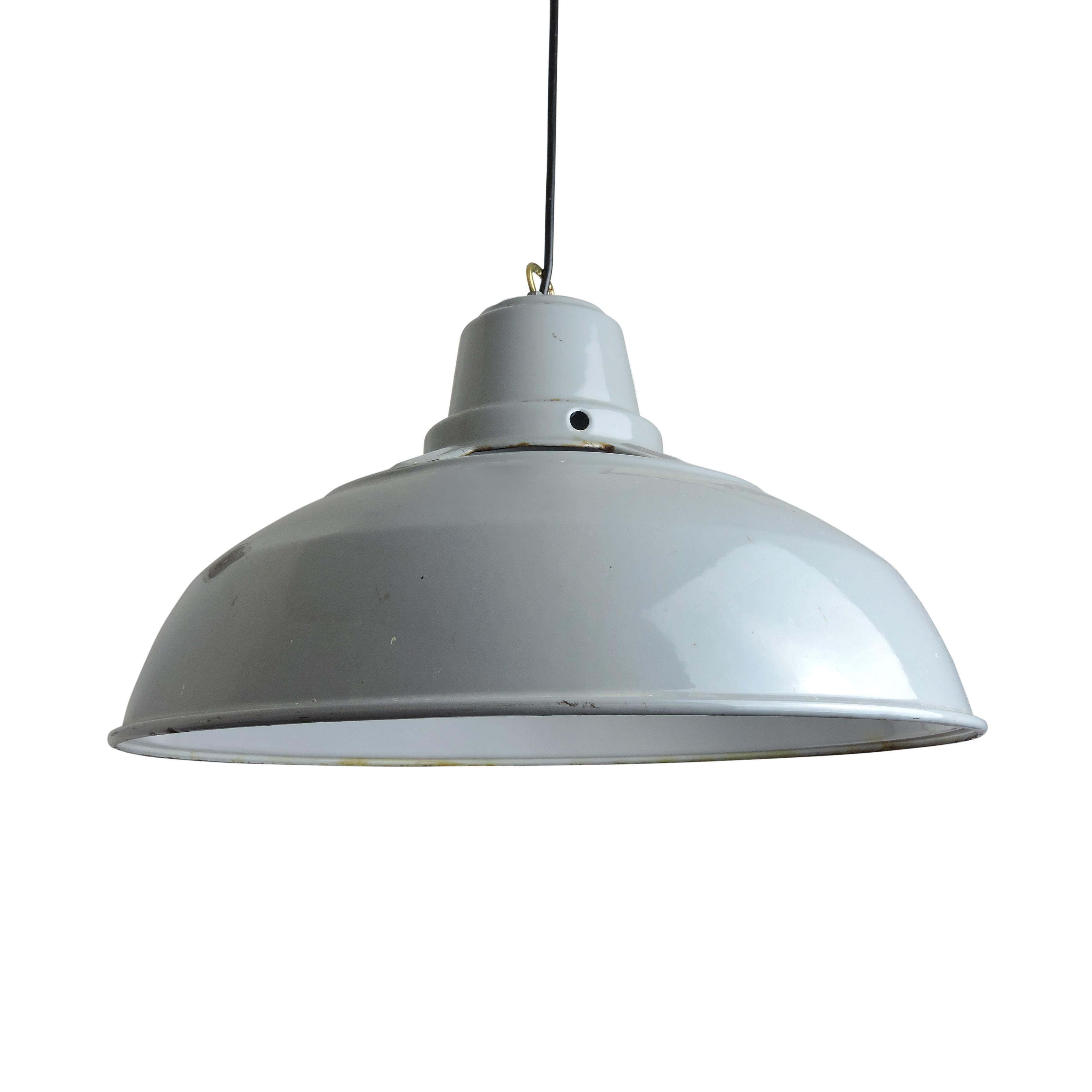 A grey industrial pendant light, which features a cutout design and white livery.