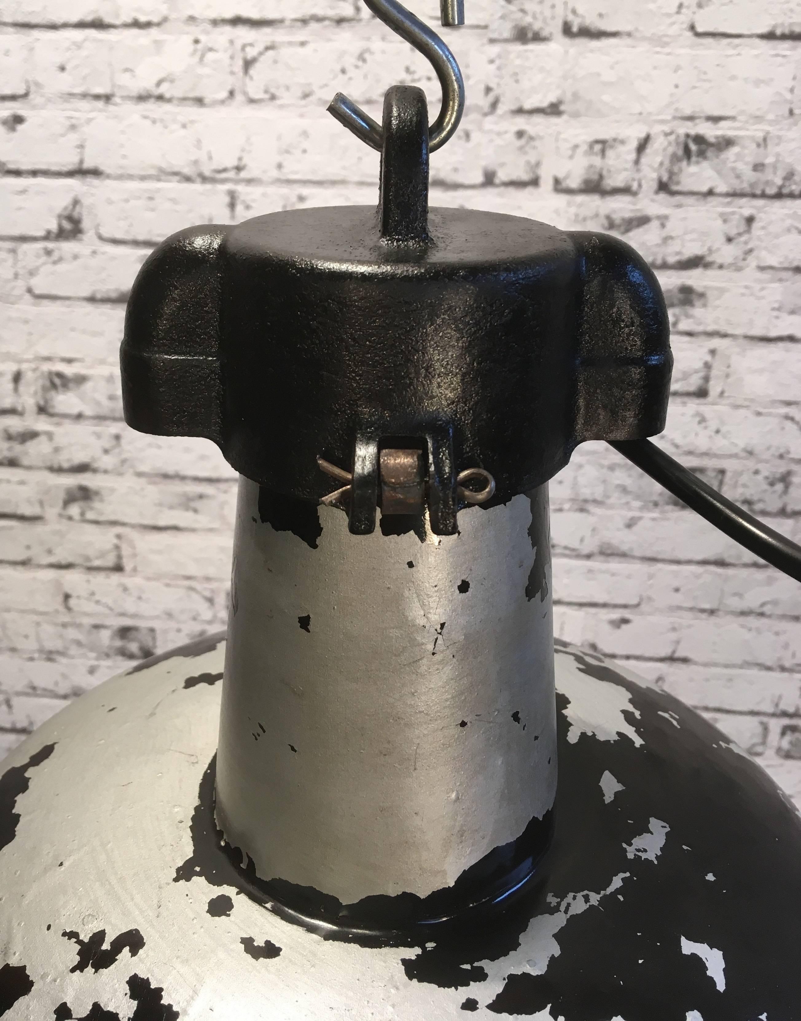 Industrial hanging lamp from  the 1950s.Previously black enameled lamp was painted on grey.
Now lamp has an interesting patina. New porcelain socket E 27 and wire.Cast iron top.