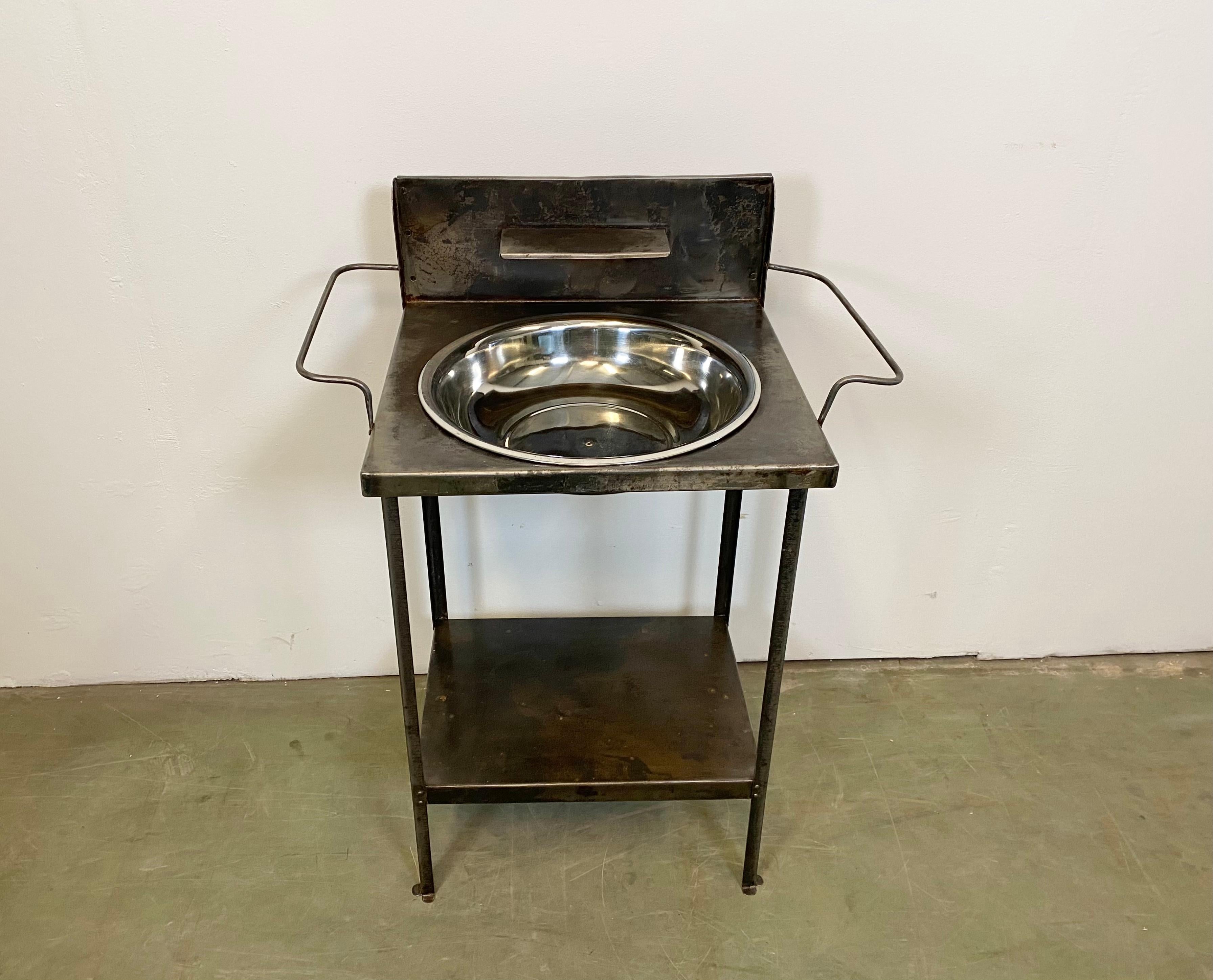 - Vintage, industrial, brushed hospital wash basin.
- Made during the 1960s.
- It features a metal, 2-tier construction and a stainless steel wash basin. 
- Weight: 6 kg.