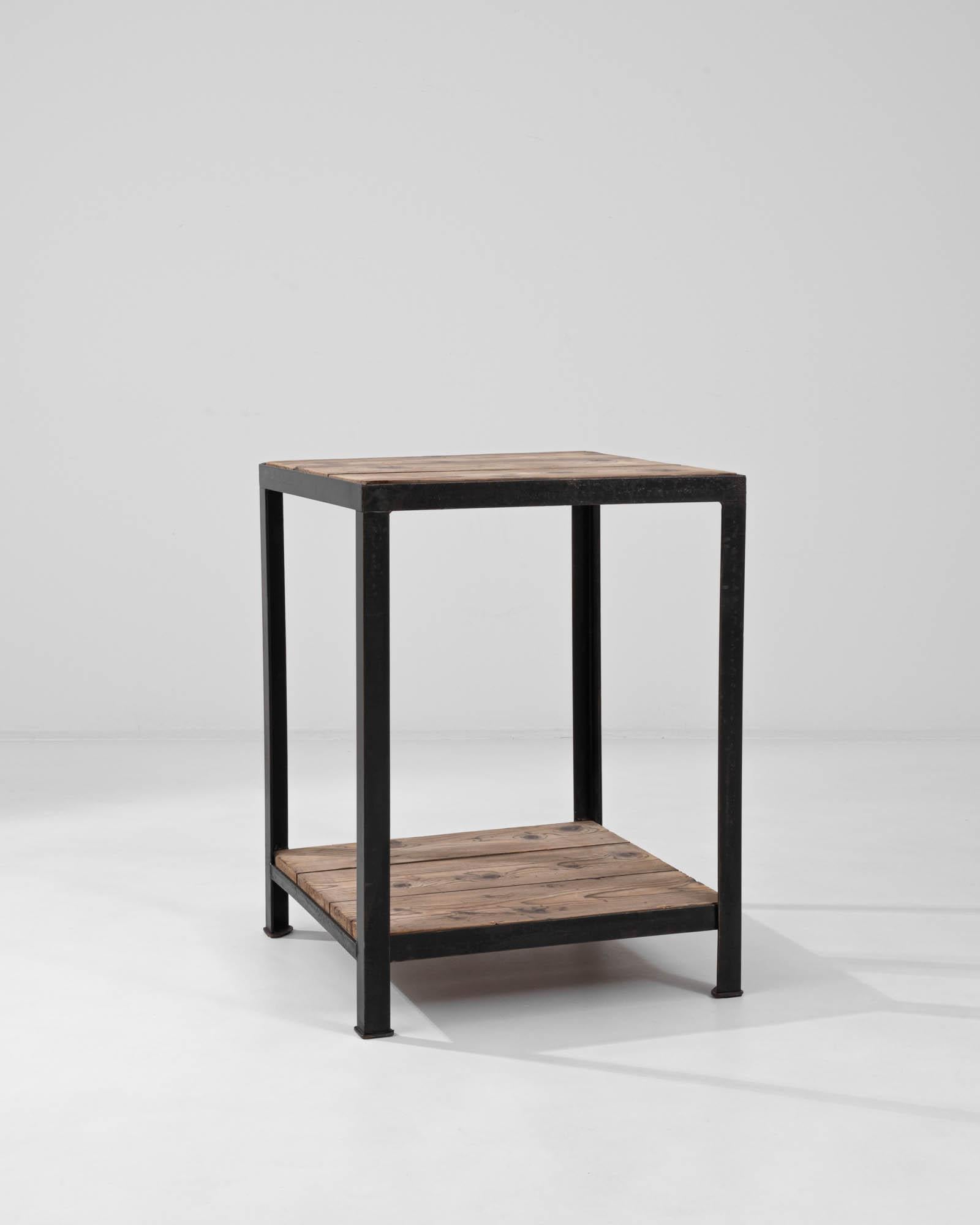 A vintage metal and wooden table from France. Constructed from square metal legs and brightly weathered wooden slats, this side table is infused with an industrial edge. A lushly colored framework of metal encases a bright tabletop and its lower