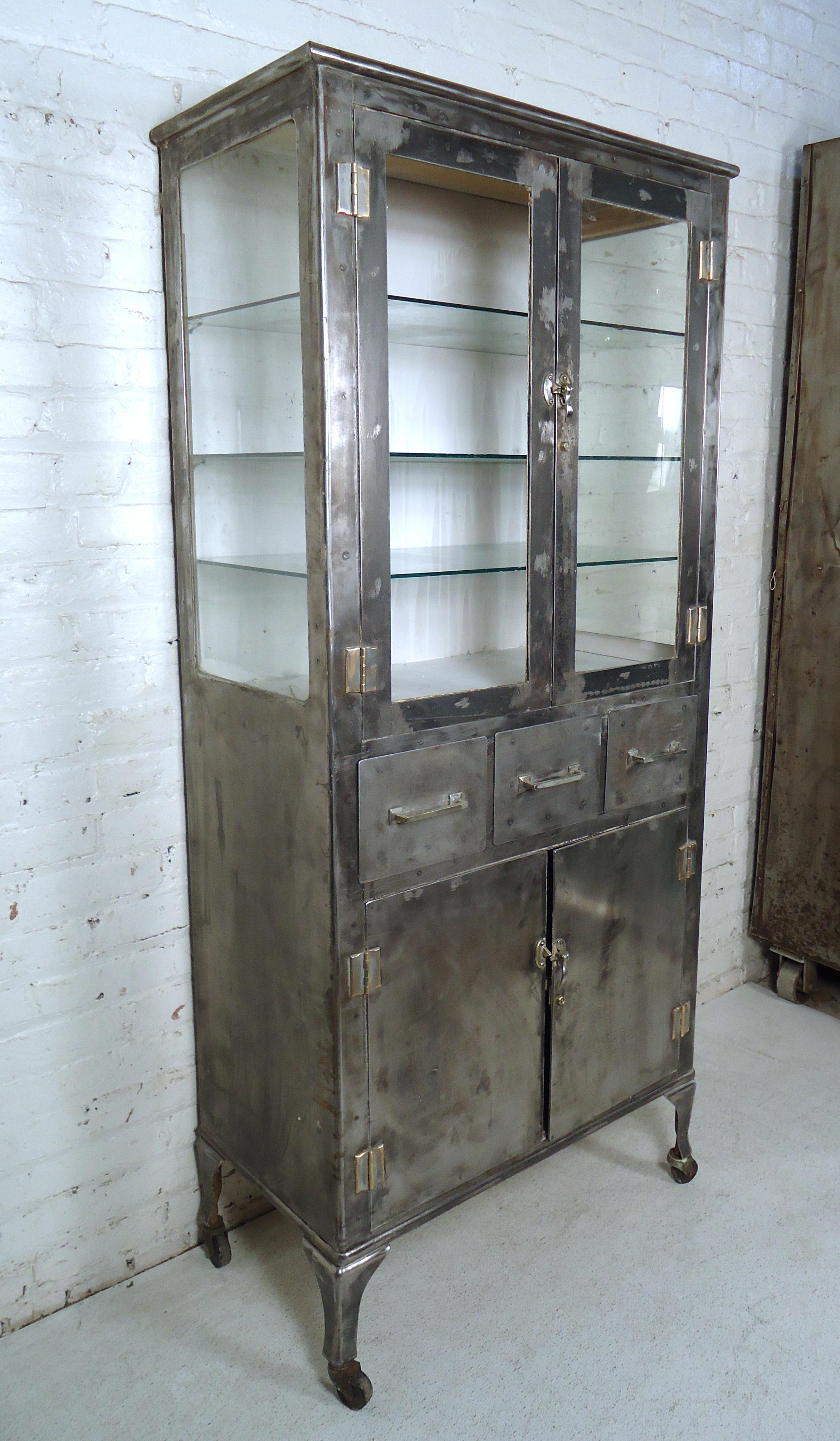 Vintage metal Doctor's cabinet, refinished in an industrial finish. Striking bare metal finish with glass sides and shelves. Rolling wheels and adjustable shelves. 

(Please confirm item location - NY or NJ - with dealer).
