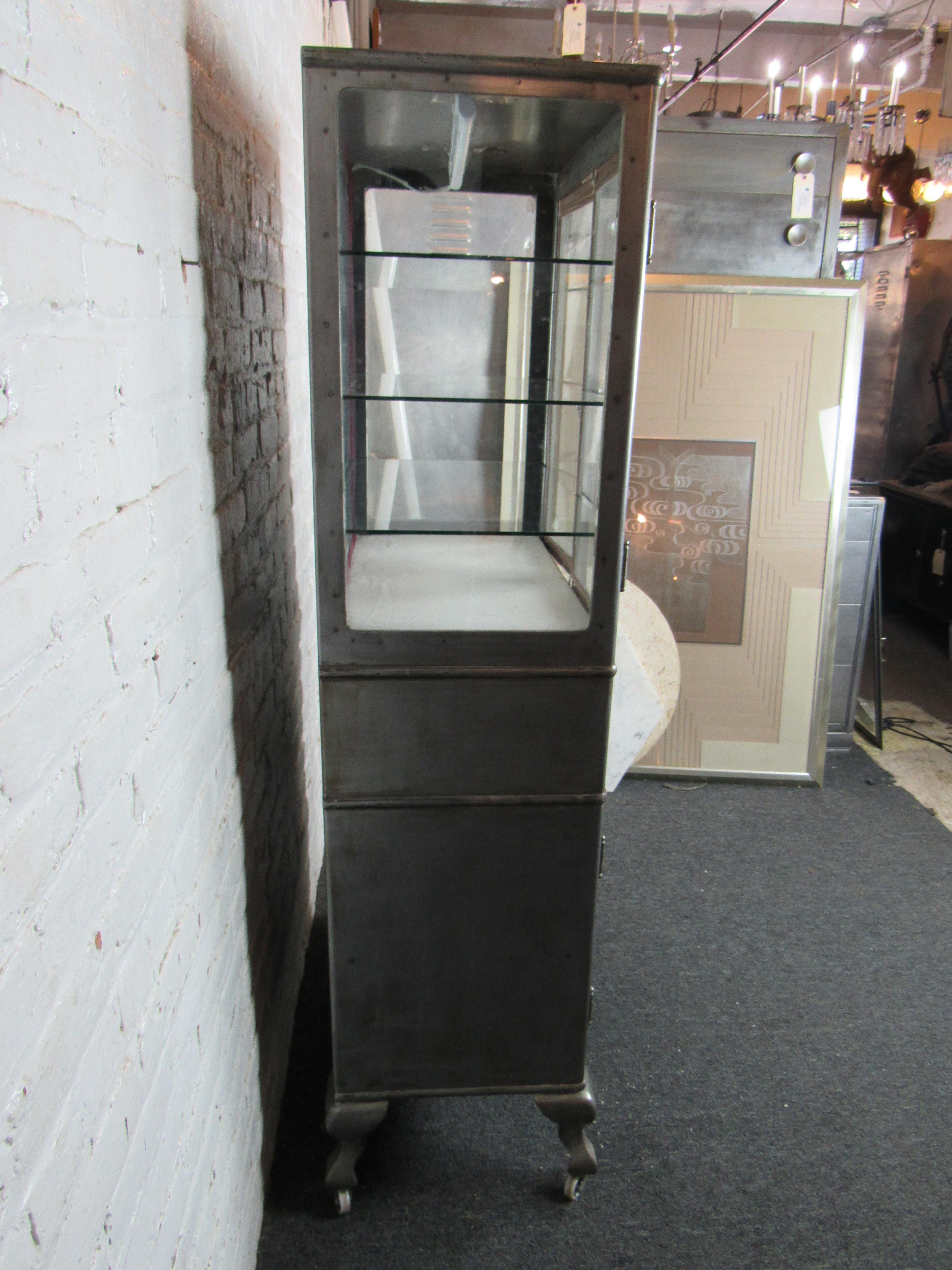 This large rolling display case is perfect for adding industrial style to any workshop or studio space. Glass shelving and a light at the back of the cabinet add a dramatic effect, while drawers and a larger storage compartment offer functional