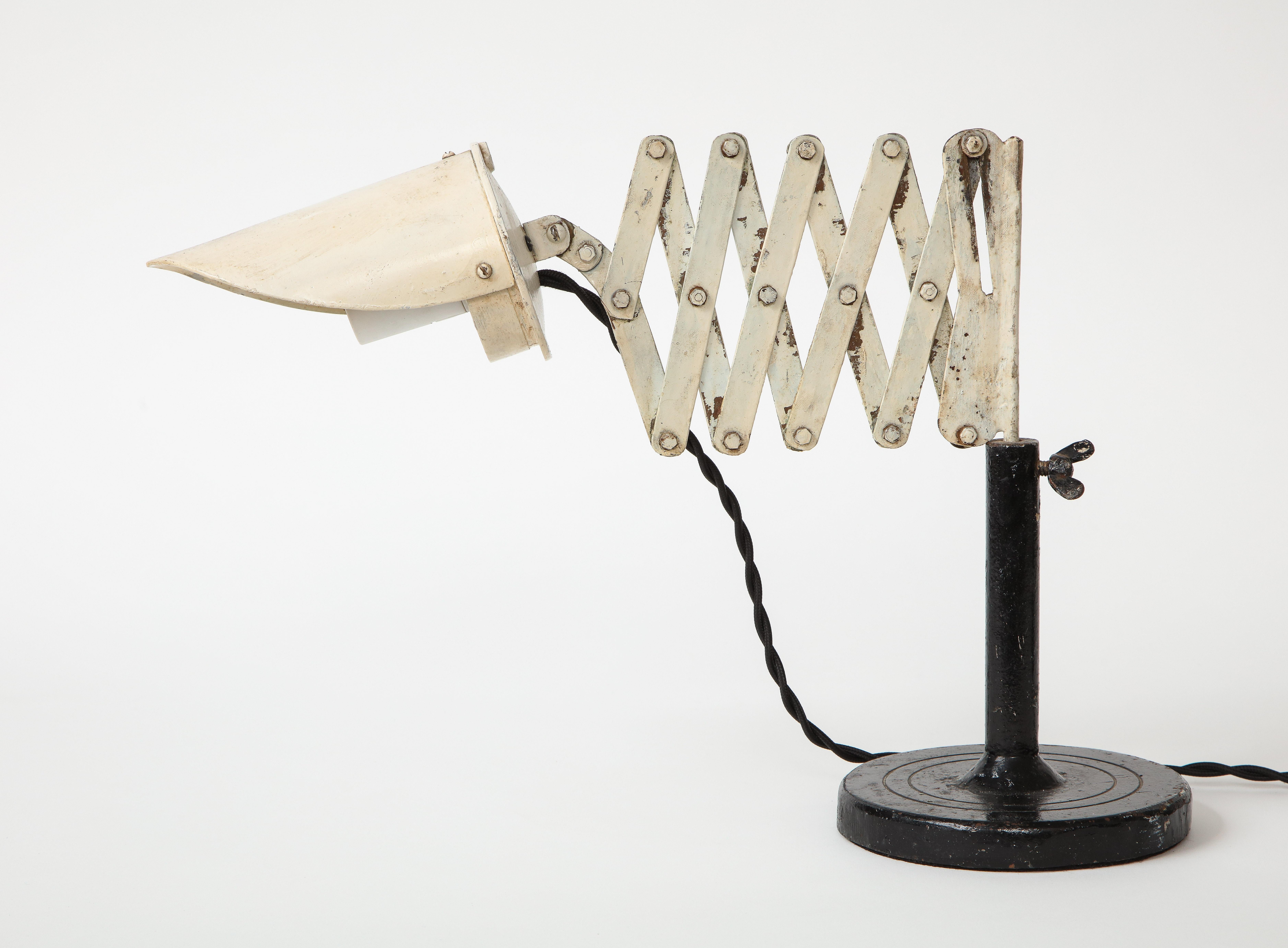 Vintage industrial metal scissor table lamp, circa 20th century. 

Lamp consists of a round base, adjustable cylindrical body, and accordion arm that extends to various lengths. The scissor lamp design was introduced in the 1930s and is a perfect