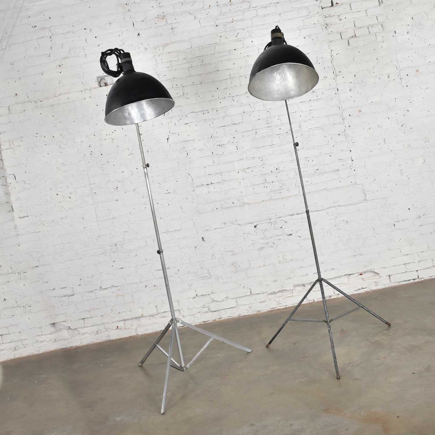Fabulous vintage Industrial pair of aluminum and steel structured photographers floor lights with tripod bases. They are in wonderful vintage condition Beat up with lots of dents and patina. Fresh coat of texture paint on shades. Please see photos.