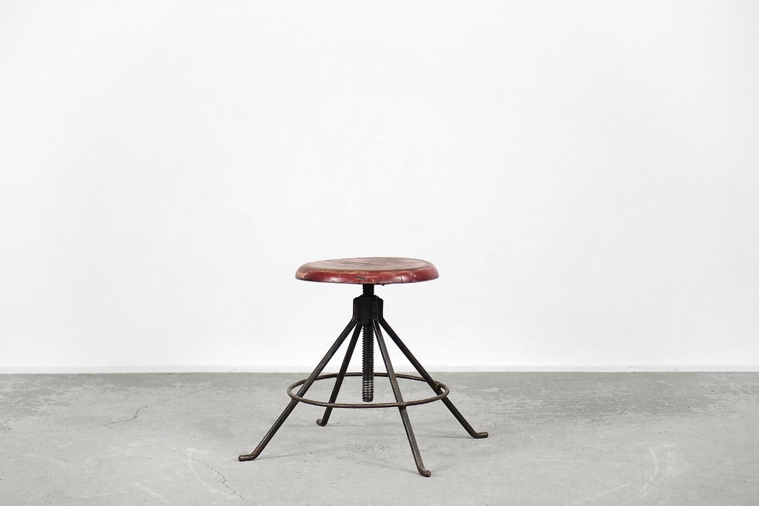 This swivel stool was made in Poland in the 1950s. The wooden, round seat in shades of red is mounted on a solid metal screw. Four metal legs are connected to each other. The seat can be adjusted from 44 cm to 69 cm. It will be perfect for