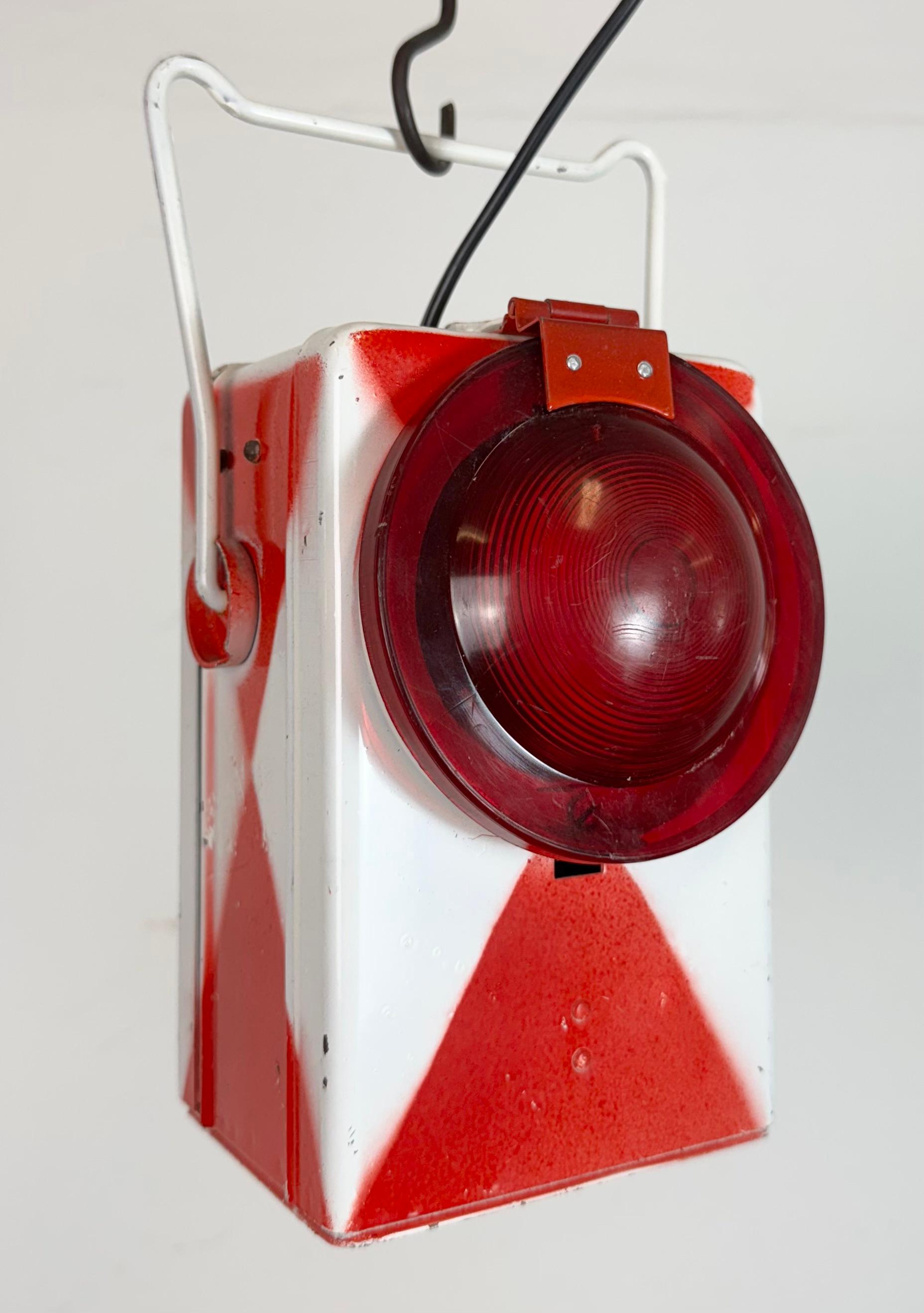 Farol industrial vintage para ferrocarril fabricado por Kovo Věšín en la antigua Checoslovaquia durante la década de 1980. Presenta un cuerpo metálico rojo-blanco y una tapa de cristal de plástico rojo. Recién electrificado. La toma requiere 