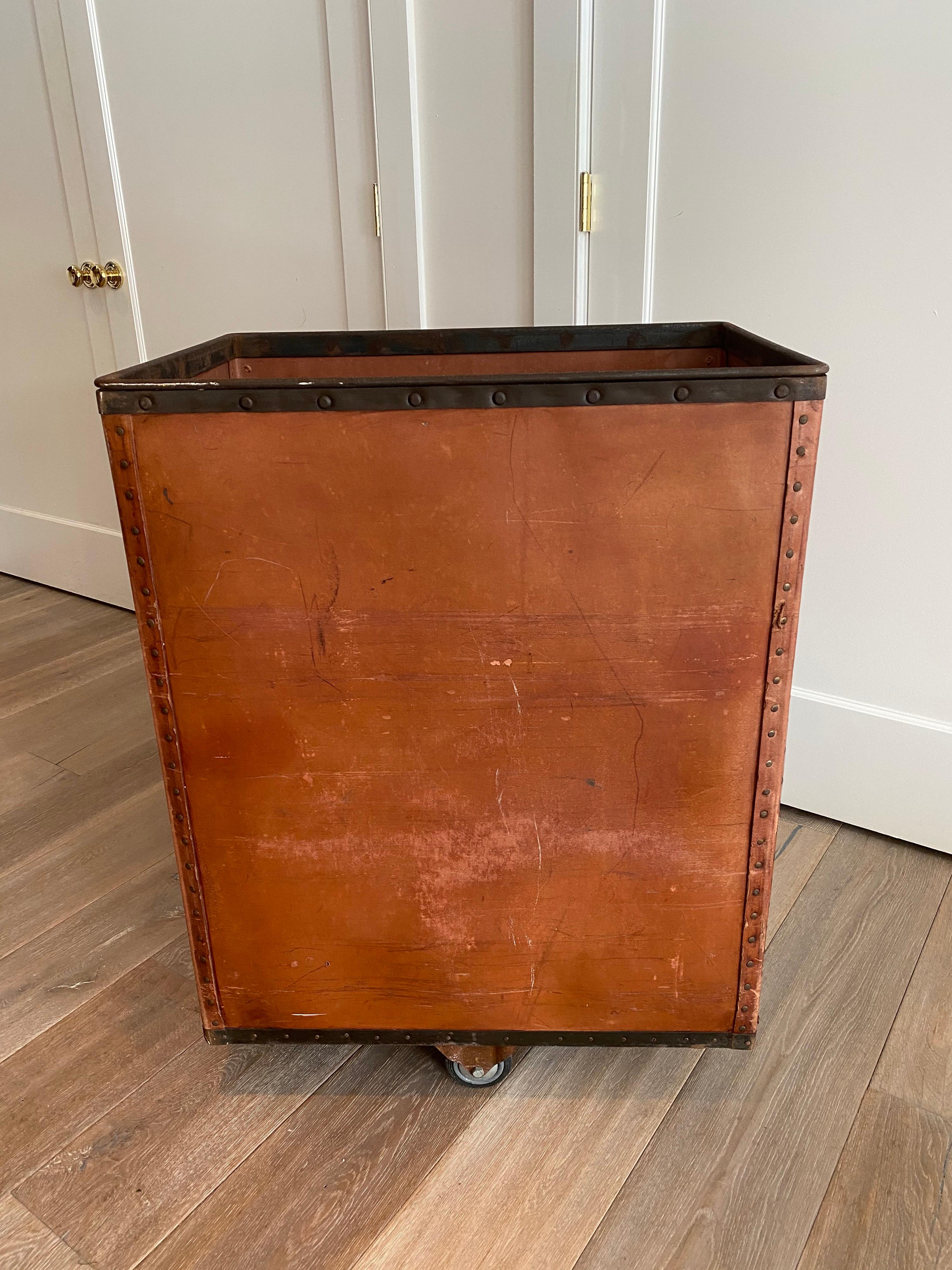 A vintage Industrial factory box car by FedCo fibre bin, circa 1950s. With burnt orange basin. walls, metal riveted framing and wood plank base on four castors. A great bin for display or storage. Strong and sturdy construction- wheels role