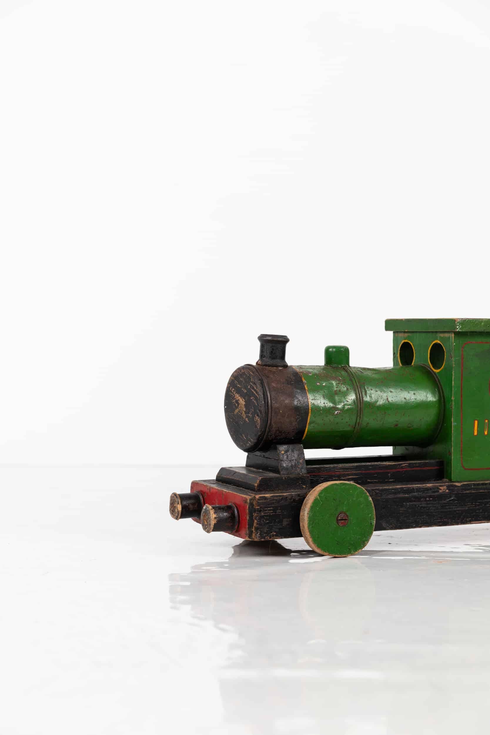 A wonderfully formed green painted toy train. c.1940.

Likely scratch built, made of wood and metal and all in original paint with letters and numbers sign written to the sides. One wheel has been replaced at some point in its life.