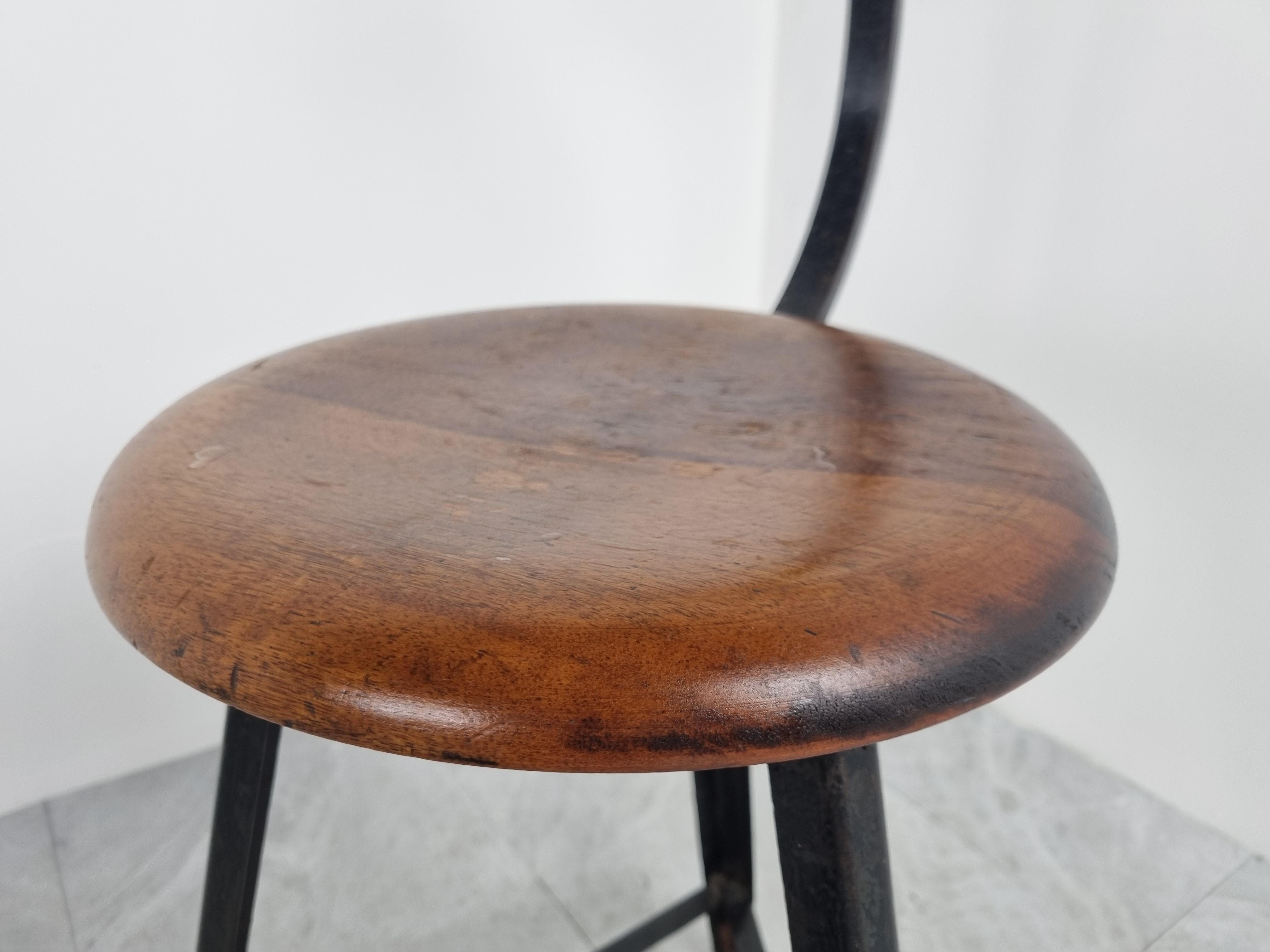 Great looking vintage tripod base factory stool with a backrest.

Made from a black metal base, anicely crafted round wooden seat and backrests.

Beautiful wear, even with an original sticker from the Brussels based manufacturer.

1950s -