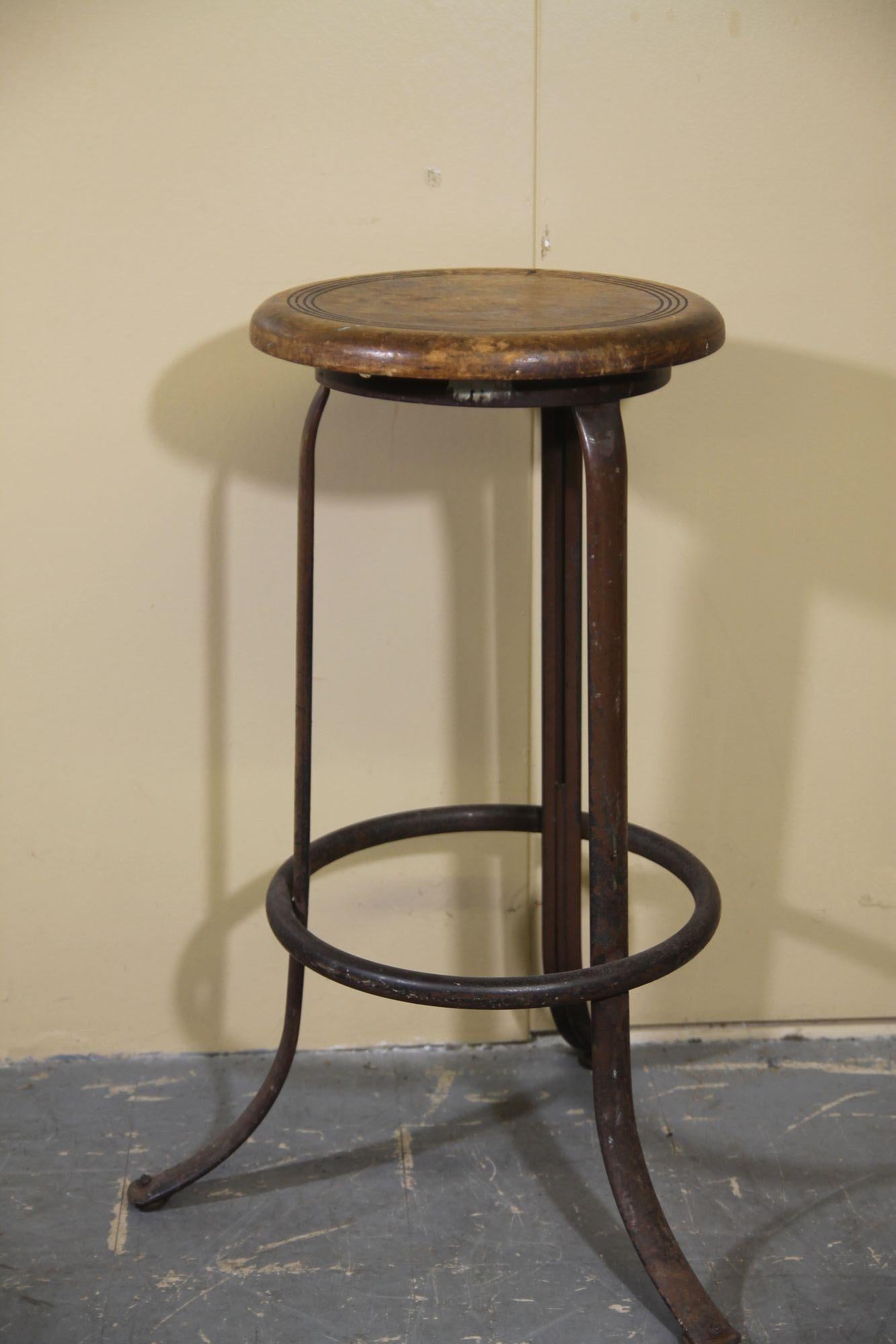 Pleased to offer this great industrial stool with wood seat and metal base. The metal base has a dark burgundy finish. The base also has the foot rest ring on it.
