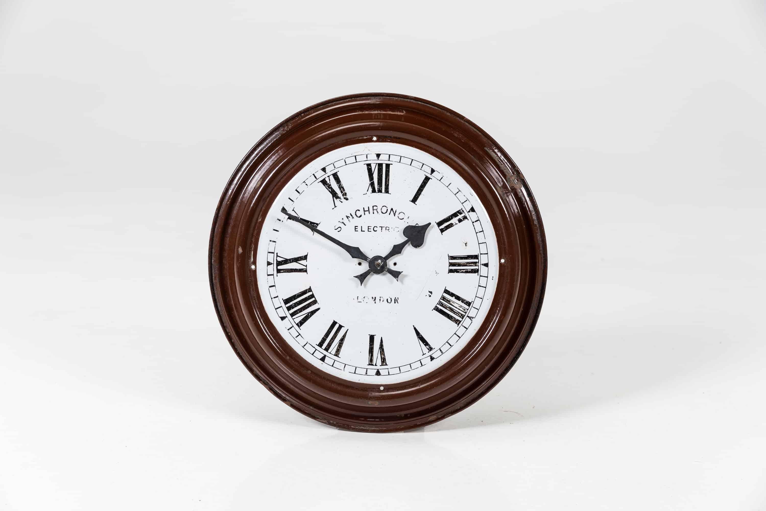 A simply formed one piece enamel wall clock made by Synchronome. c.1930

Formerly slave clocks made from a single piece of enamelled steel featuring roman numerals. Glass and external bezel missing. The spaded hands now running on a high torque