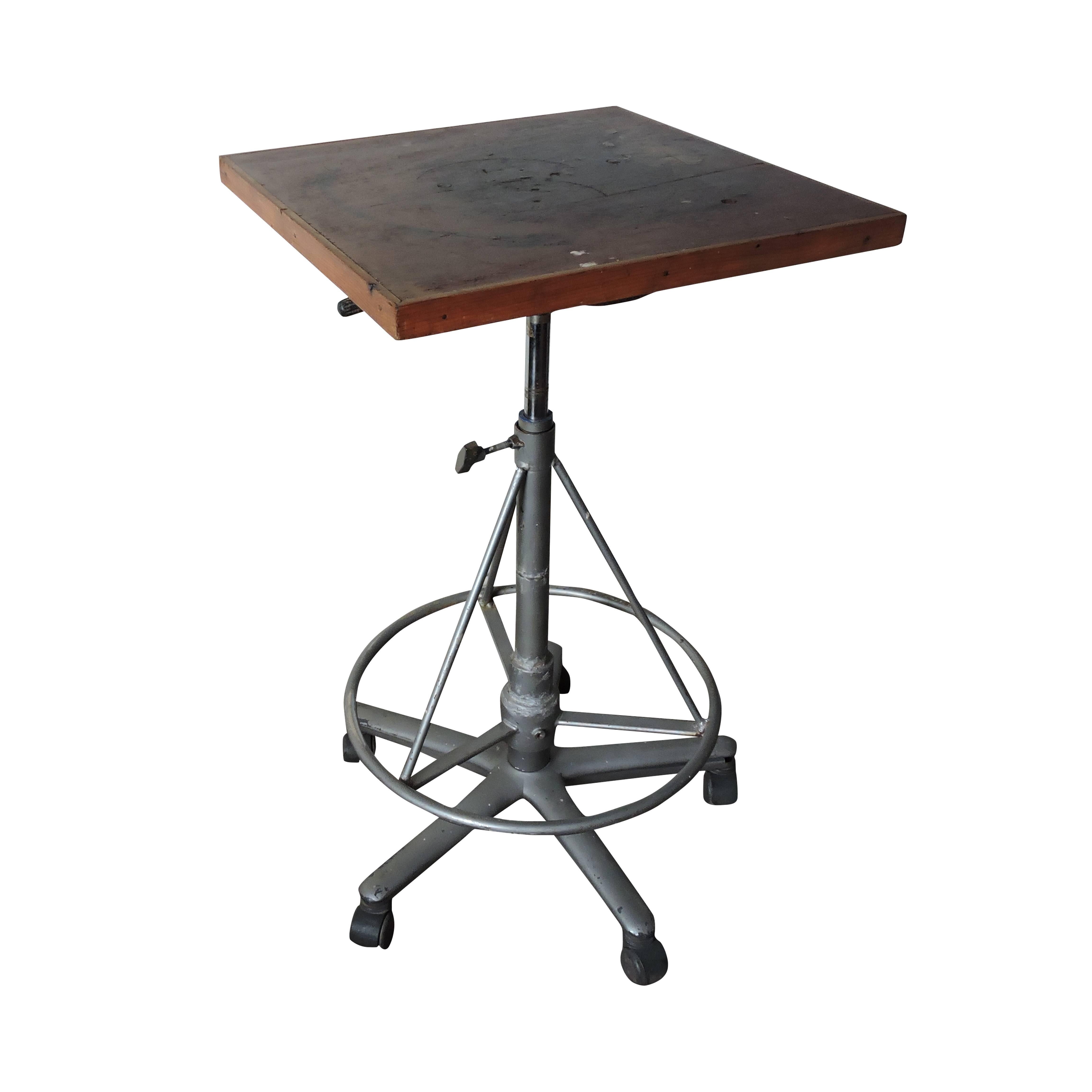 This Industrial painting and pottery table has a wooden top. It is adjustable and features a star base with wheels. Maximum 112cm - minimum 36cm. Table is sturdy.
