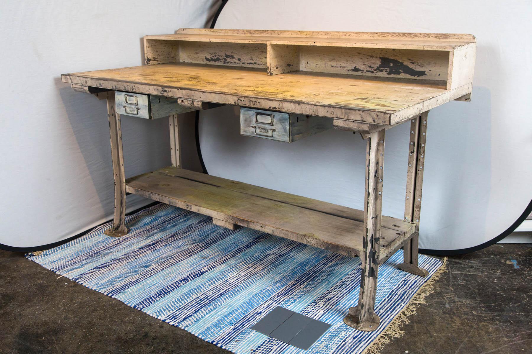 Steel leg wood top workstation with cubbyholes and drawers.