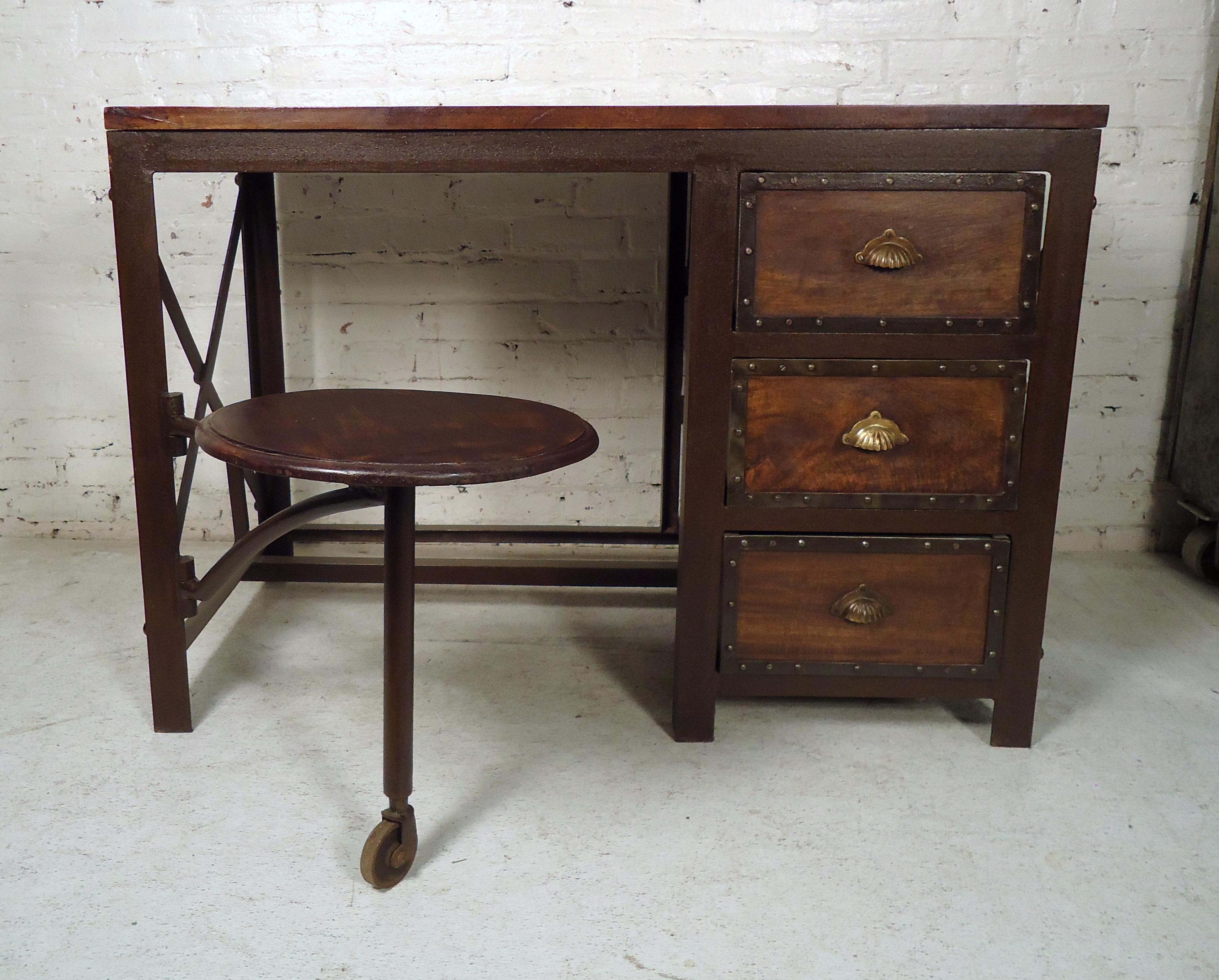 This unique vintage modern desk features rich wood grain, metal frame, three spacious drawers with brass pulls and swing out stool. 
(Please confirm item location, NY or NJ, with dealer).