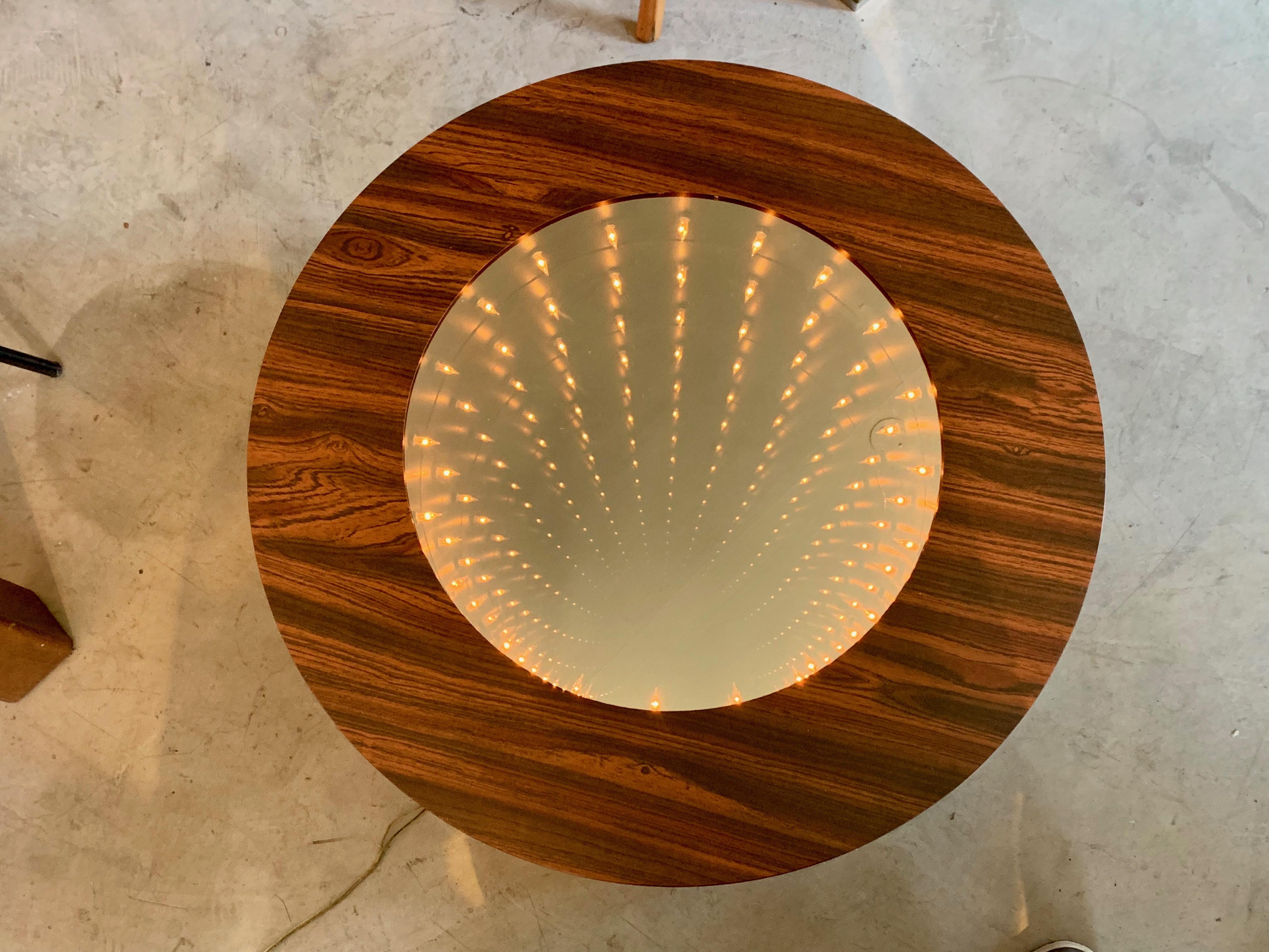 Super cool infinity mirror side table. Functional piece of art! Table is covered in wood veneer. Great condition. Infinity mirror inside is newly rewired. On/off switch on side of table.

  